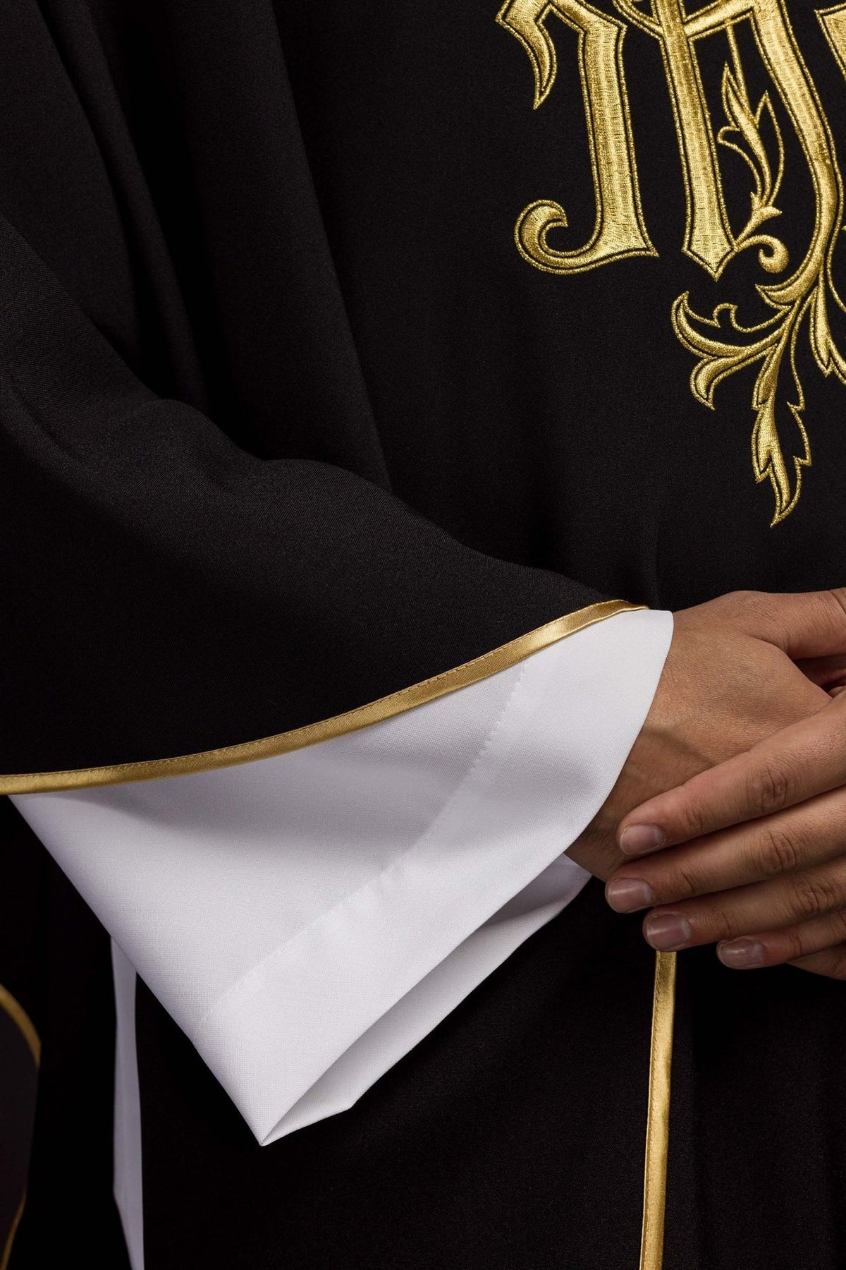 Black IHS chasuble front detail with gold trim and white sleeves
