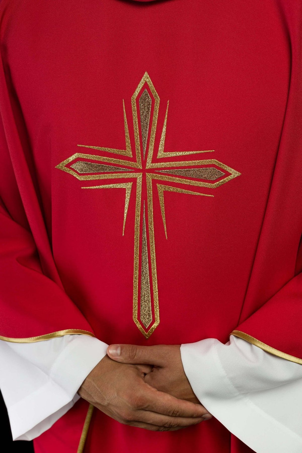 Red chasuble close-up showing gold embroidered cross design