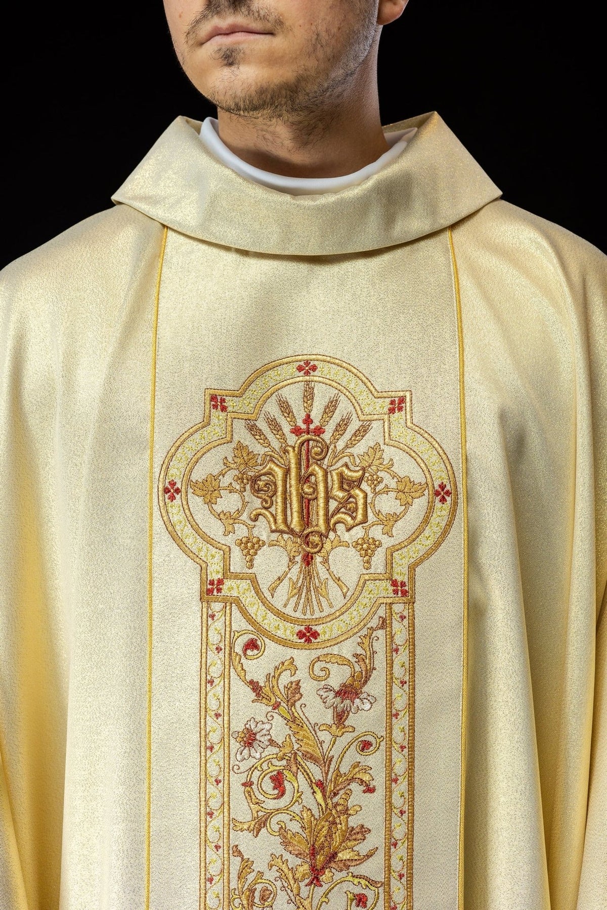 Gold chasuble close-up showing embroidered IHS motif, floral orphrey and stand-up collar