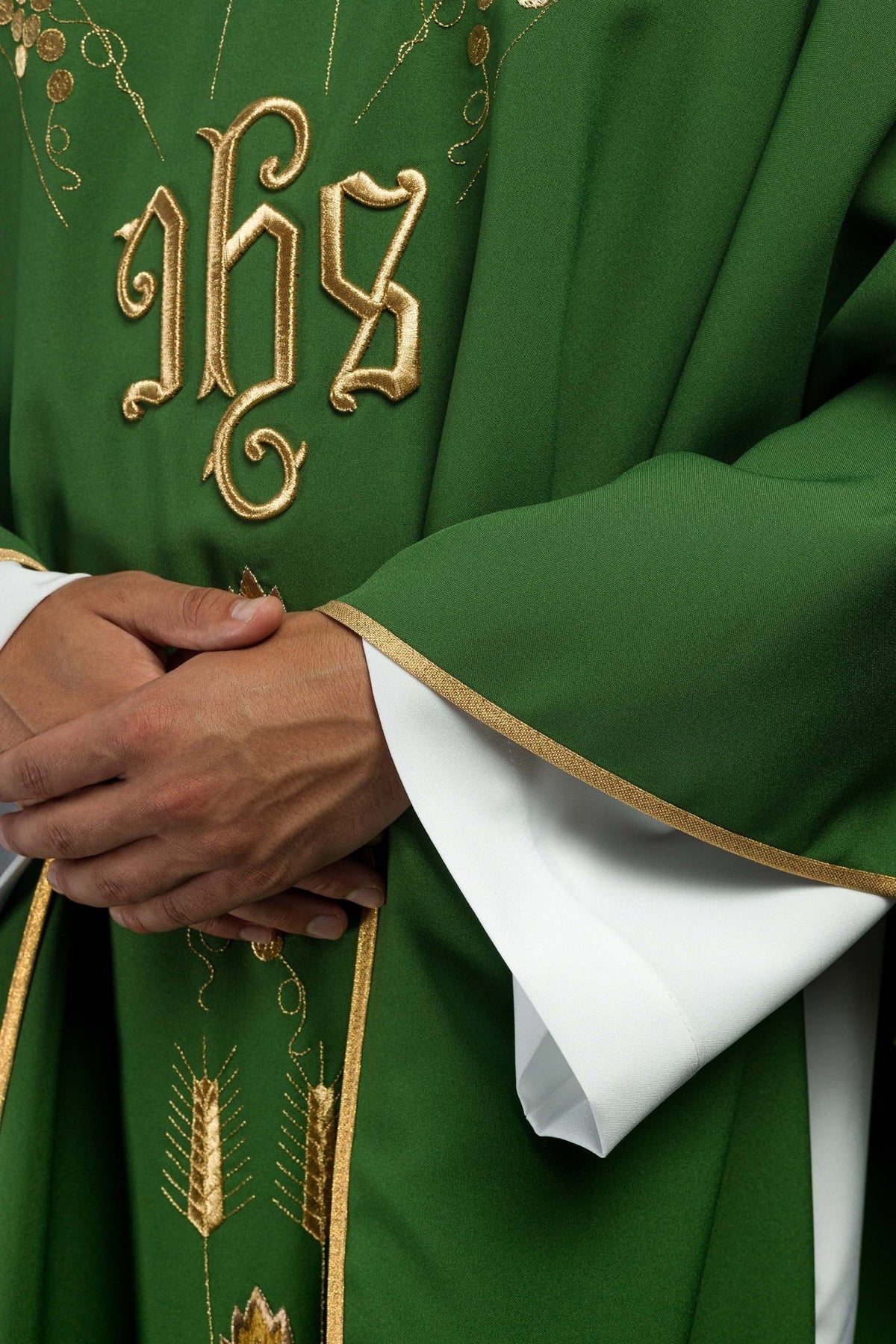 Green chasuble detail showing IHS embroidery and gold trim on the sleeve