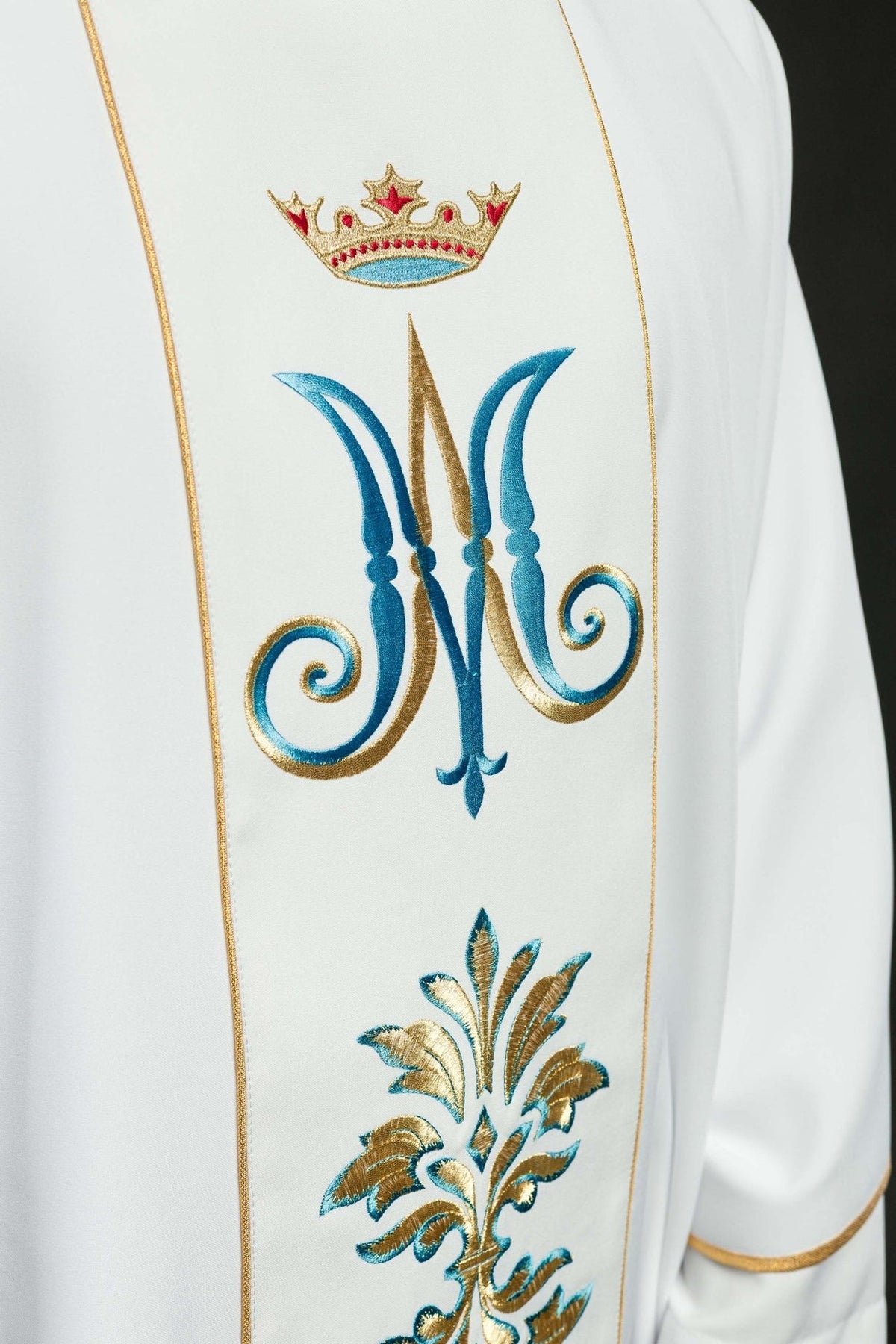 White Marian chasuble, close-up of blue and gold embroidered Marian motif and crown