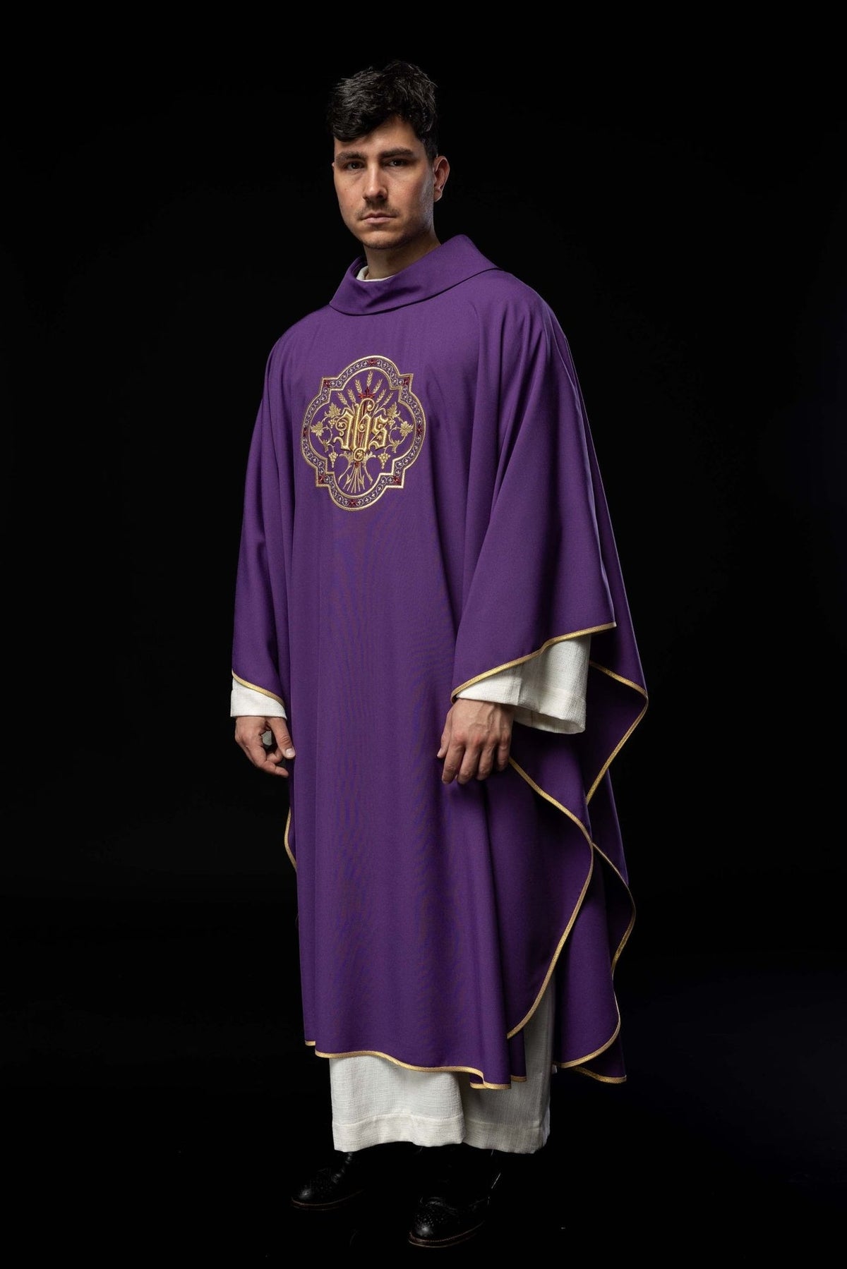 Purple chasuble side view showing flowing shape, gold trim and IHS embroidery