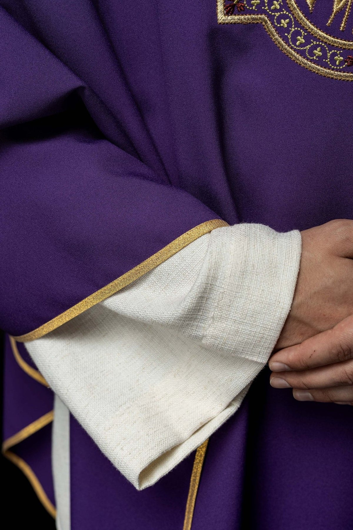 Purple chasuble fabric and gold trim close-up at the sleeve edge