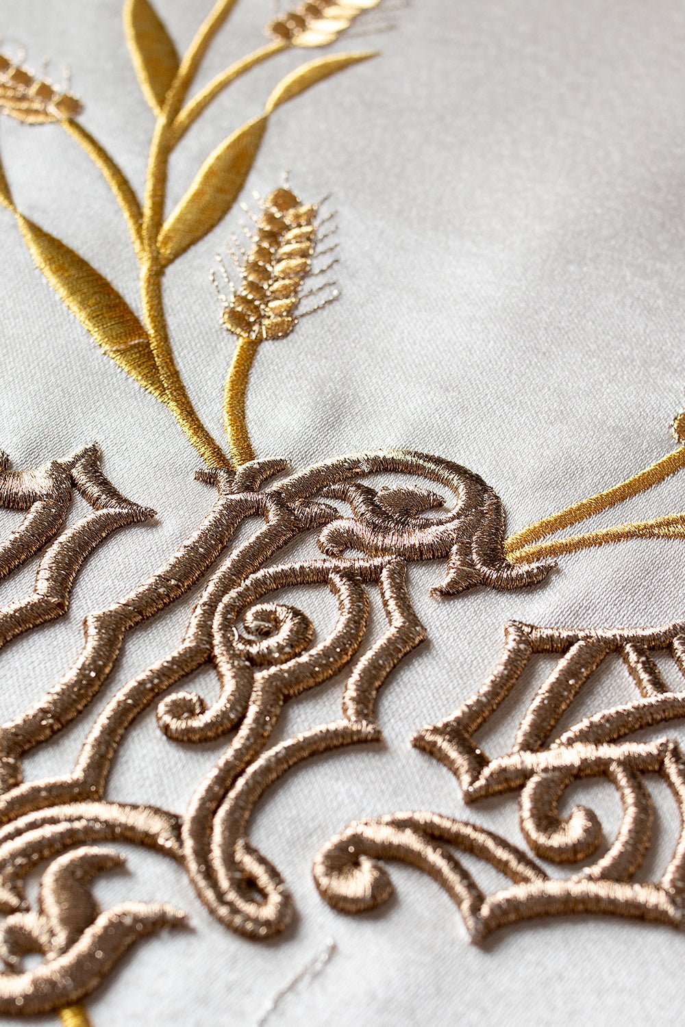 Roman chasuble close-up showing gold IHS and wheat embroidery on ivory satin
