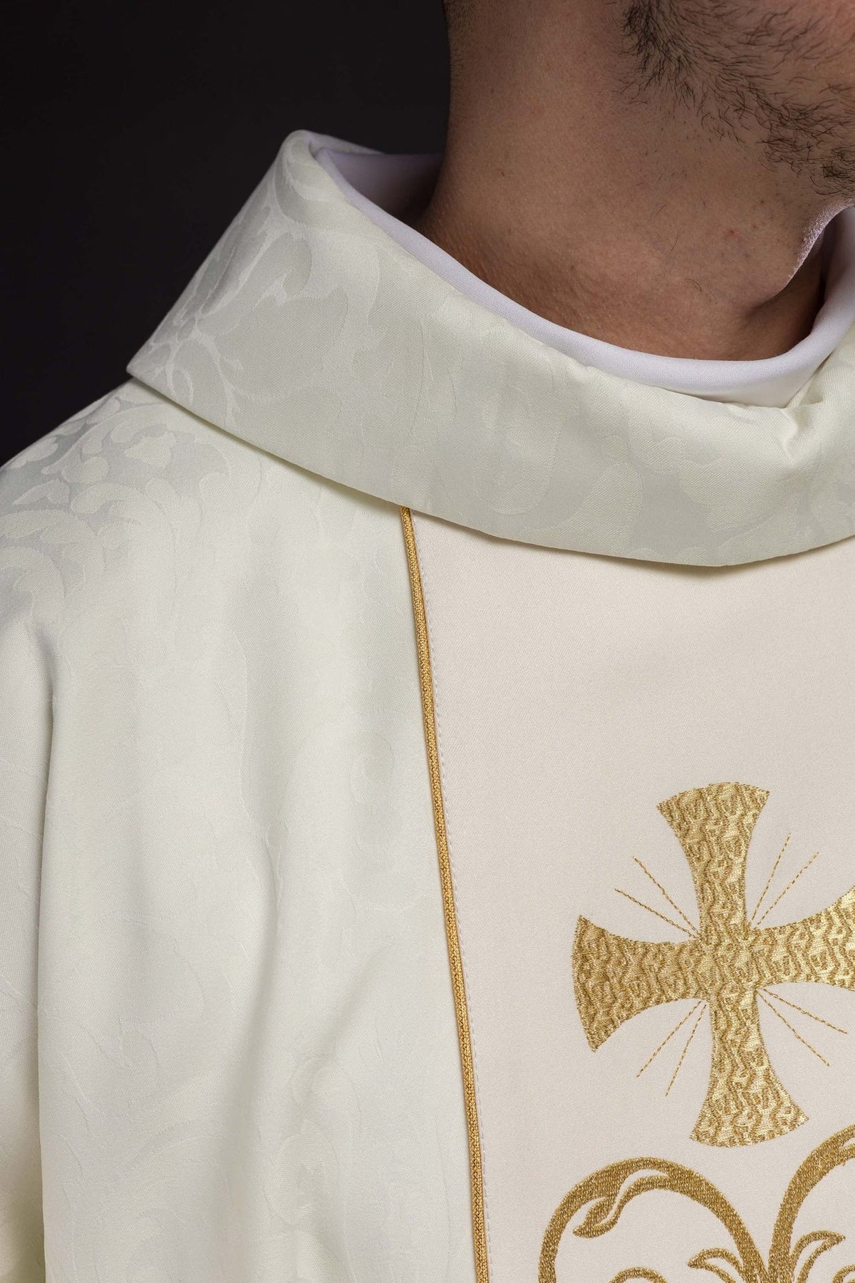 Liturgical chasuble detail showing gold cross, wheat and scrolling embroidery on the ivory orphrey