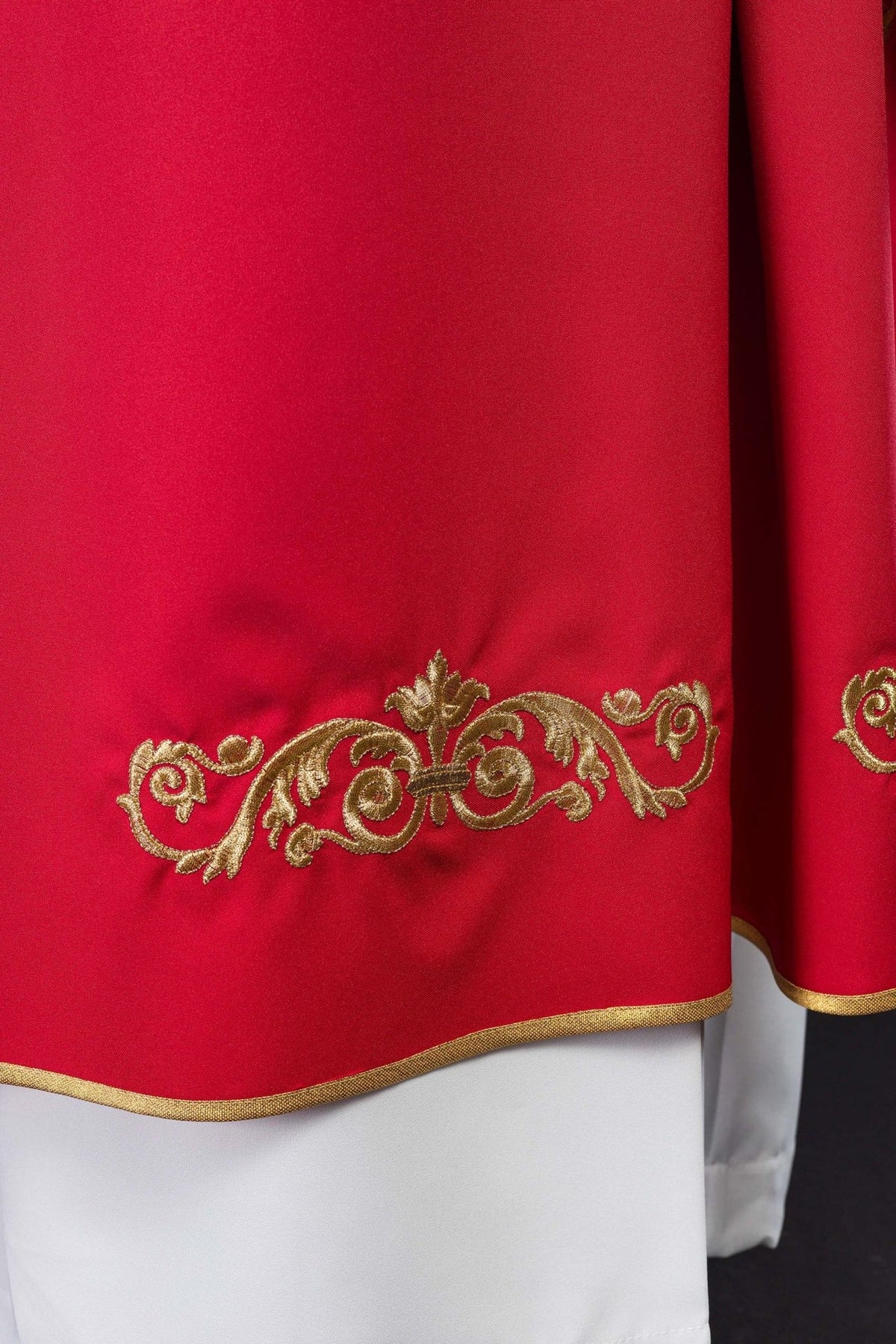 Red chasuble close-up showing gold sleeve embroidery and trim