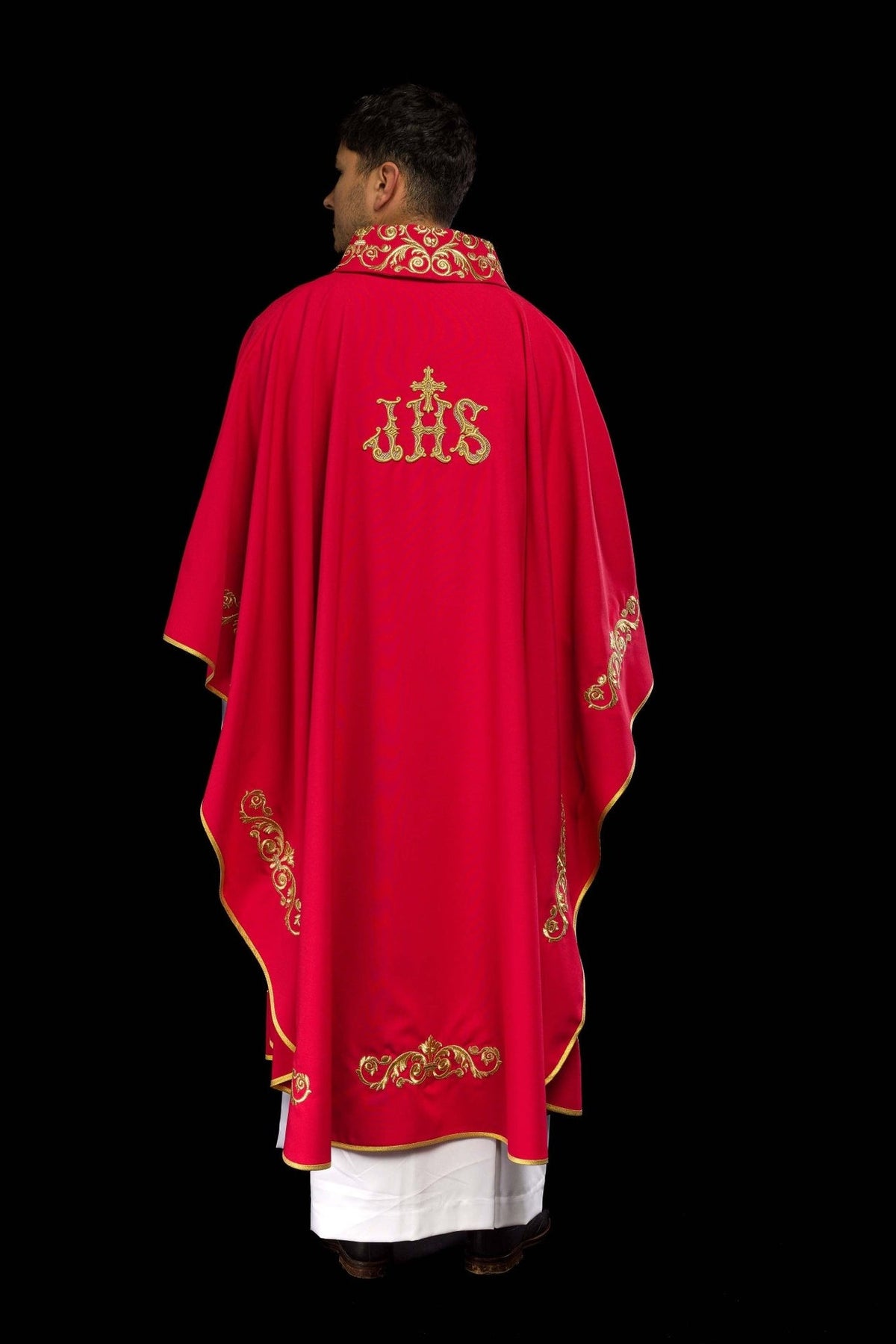 Red chasuble back view showing gold IHS embroidery and decorative trim