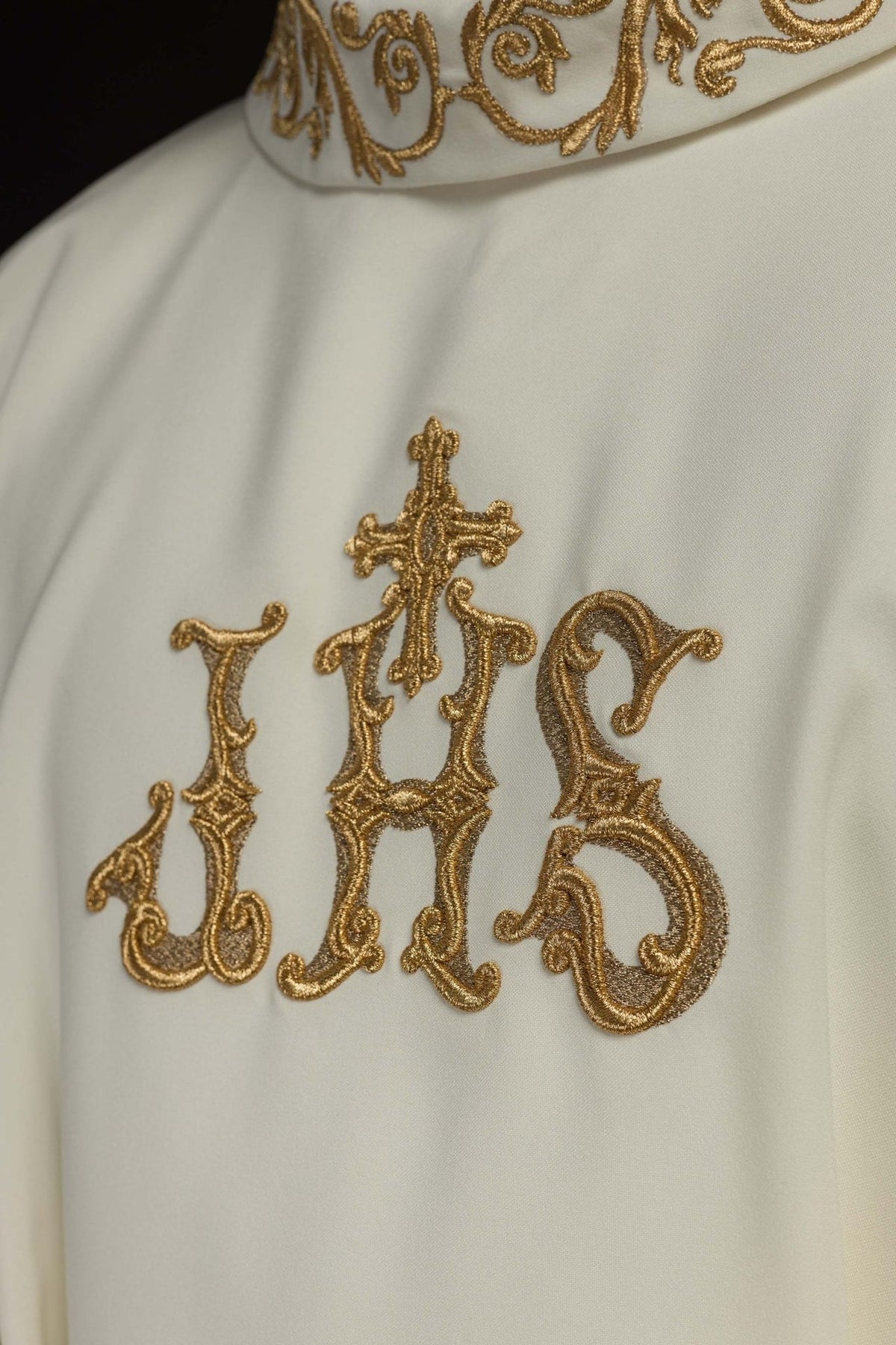 Ivory chasuble close-up showing gold IHS embroidery and stand-up collar trim