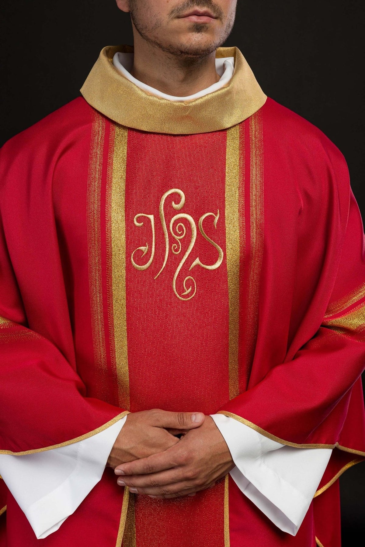 Red chasuble close-up showing embroidered IHS design, gold trim and stand-up collar