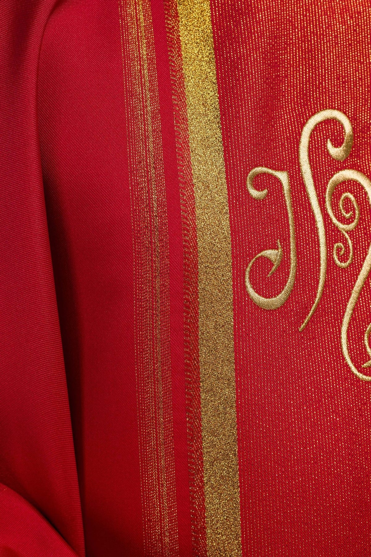 Red chasuble sleeve detail with gold trim and white cuff visible