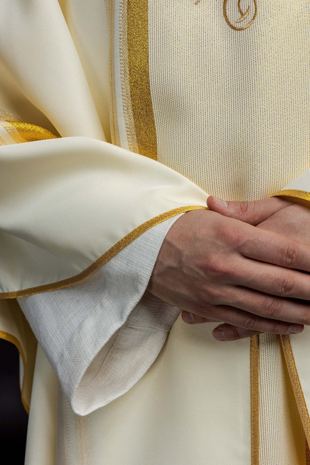 Chasuble close-up showing ivory fabric and gold vertical trim
