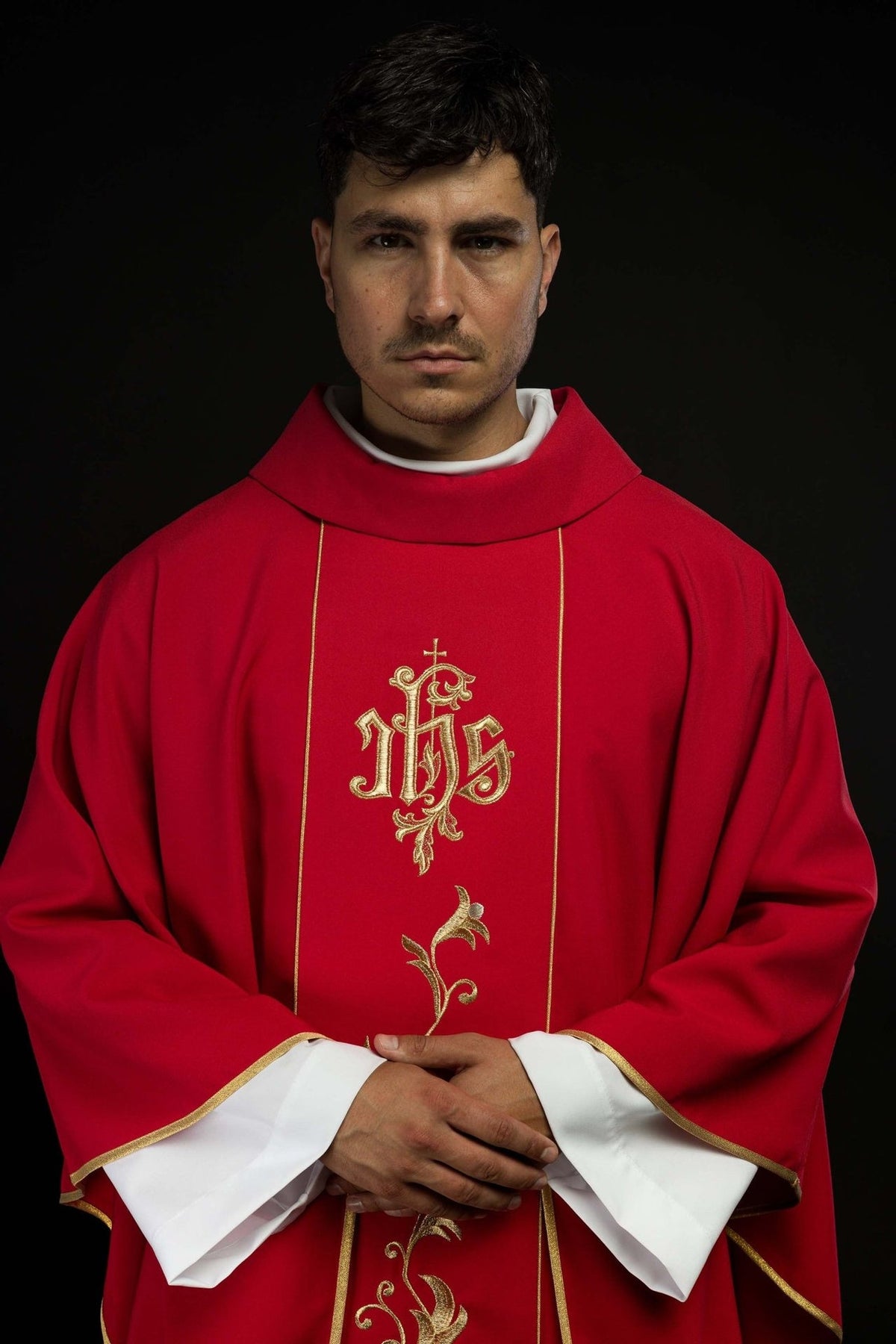 Red chasuble front close-up showing embroidered IHS orphrey and gold trim