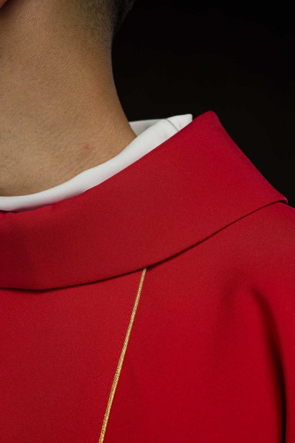 Red chasuble close-up showing stand-up collar and gold vertical trim