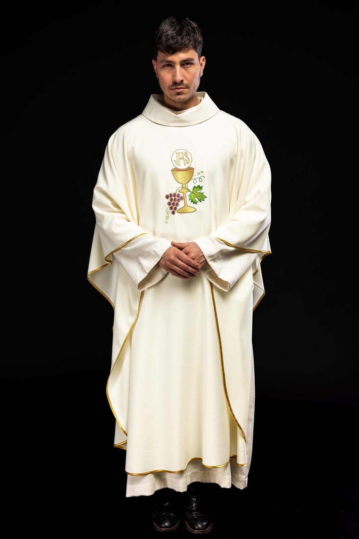 Ecru chasuble worn front view with gold trim and Eucharistic embroidery