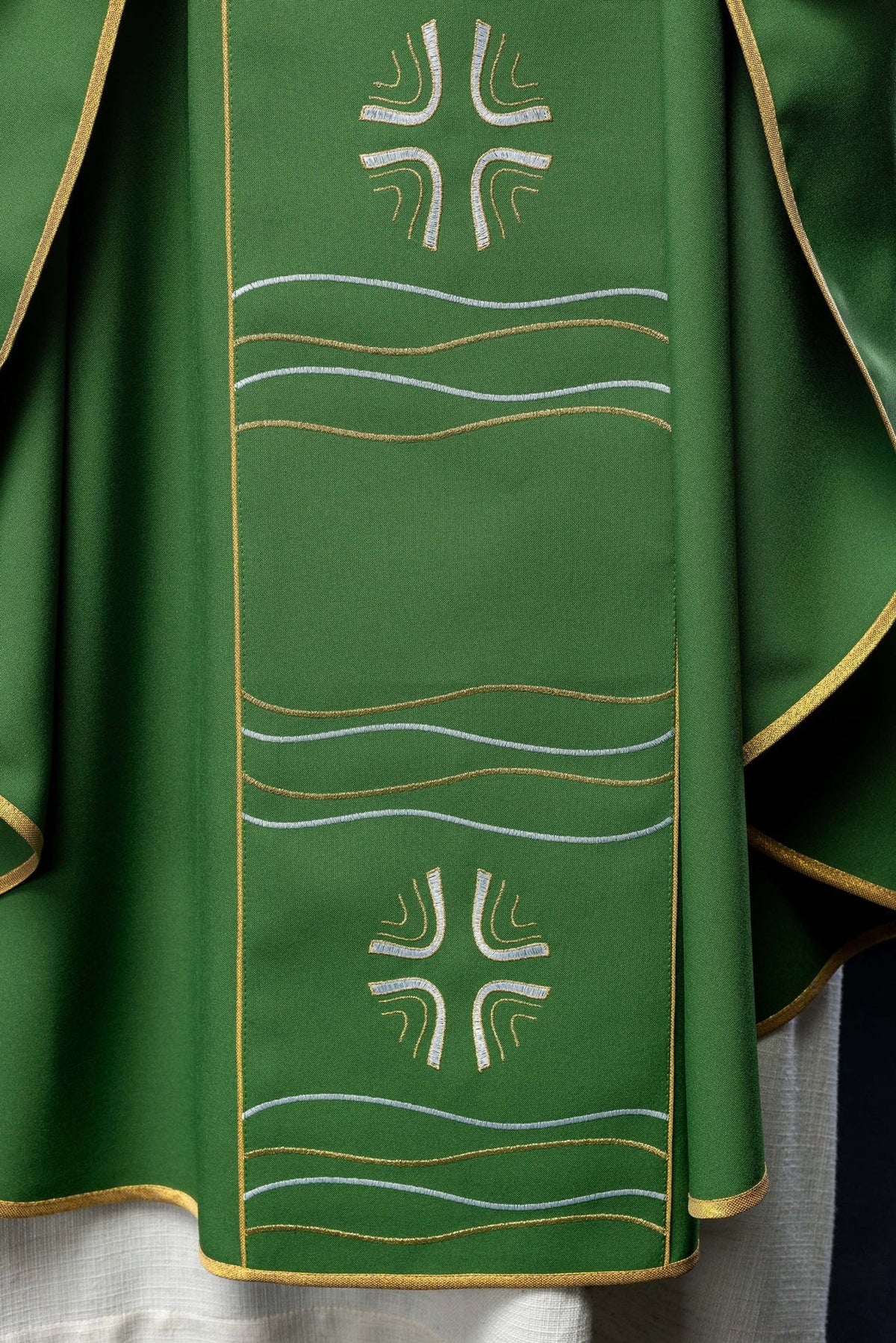 Green chasuble front detail with embroidered cross, gold trim and white wave motifs