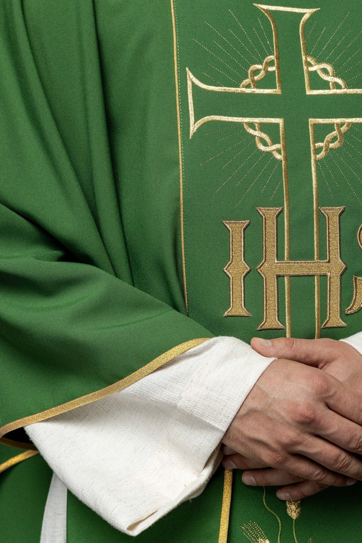 Green chasuble close-up showing gold trim, satin fabric, cross and IHS embroidery