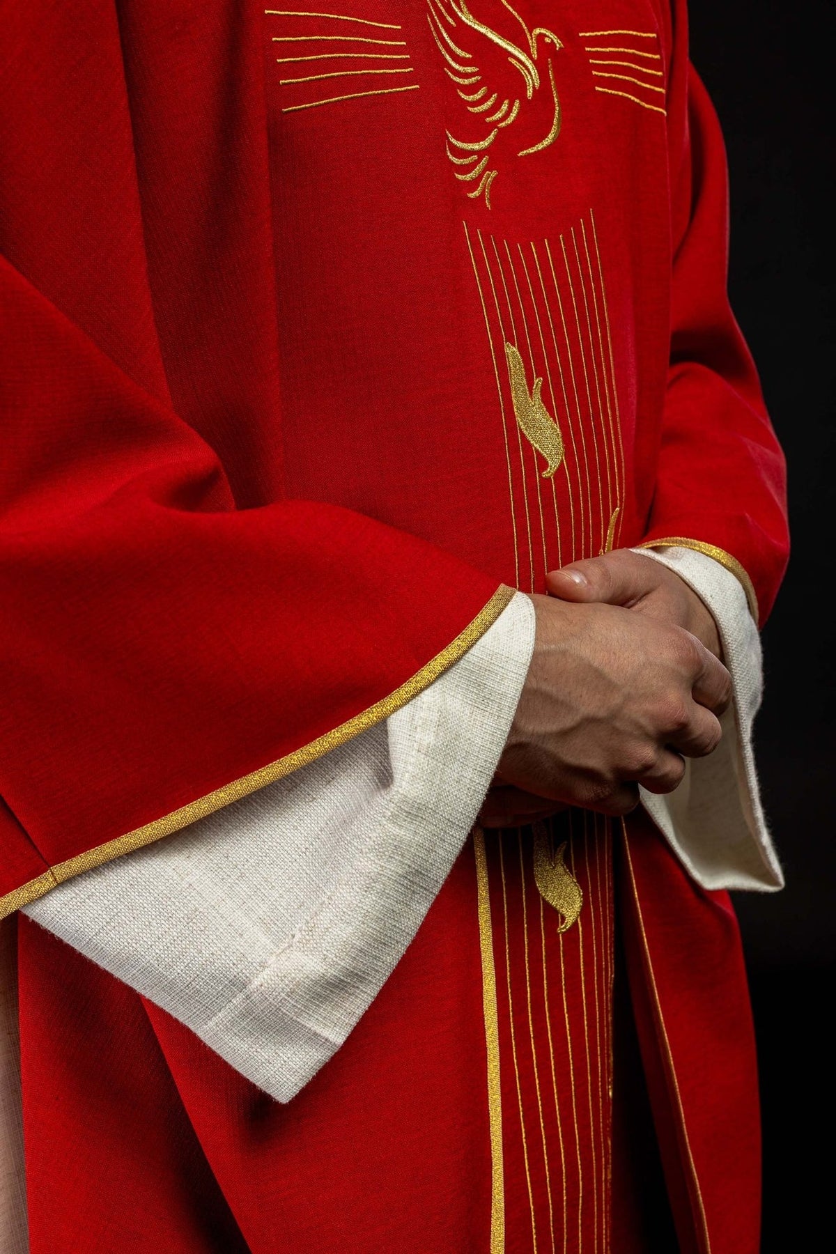 Red chasuble side close-up showing gold trim and embroidered vertical design