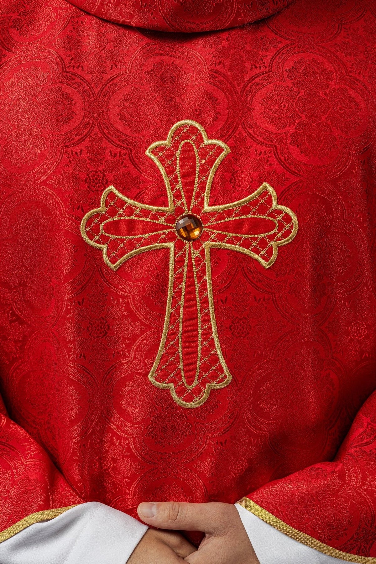 Red chasuble front close-up showing gold embroidered cross and ornate red pattern
