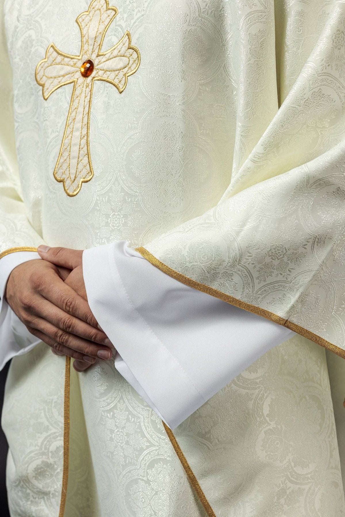 Ecru chasuble detail with gold trim, embroidered fabric and cross