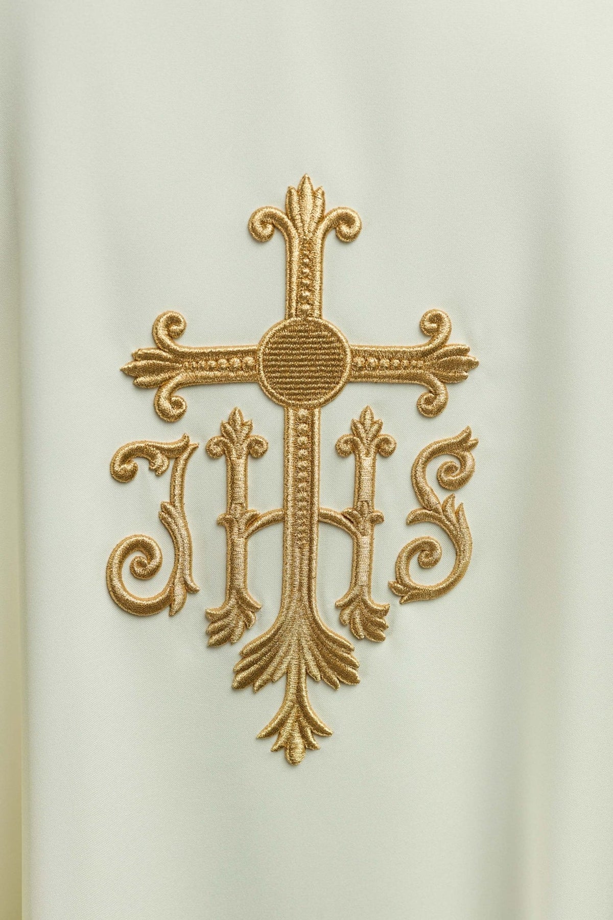 Chasuble close-up showing gold embroidered cross and IHS motif