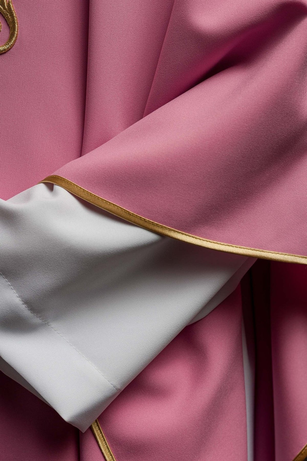Rose chasuble detail showing rose fabric, white sleeve and gold trim
