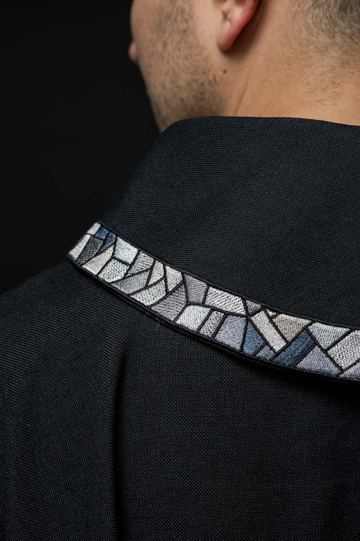 Black chasuble detail showing black fabric and white sleeve opening