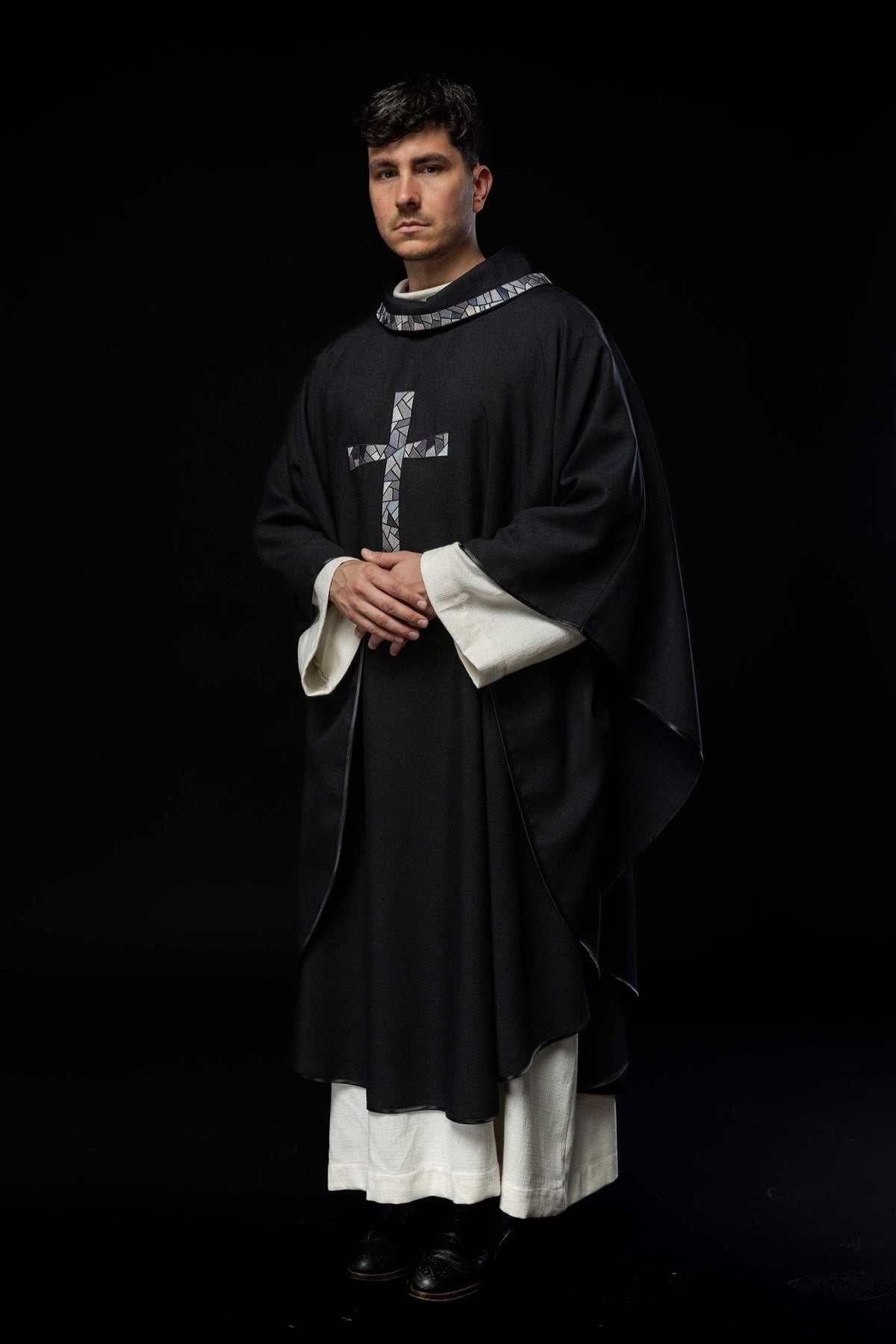 Black chasuble worn front view with mosaic cross and wide sleeves
