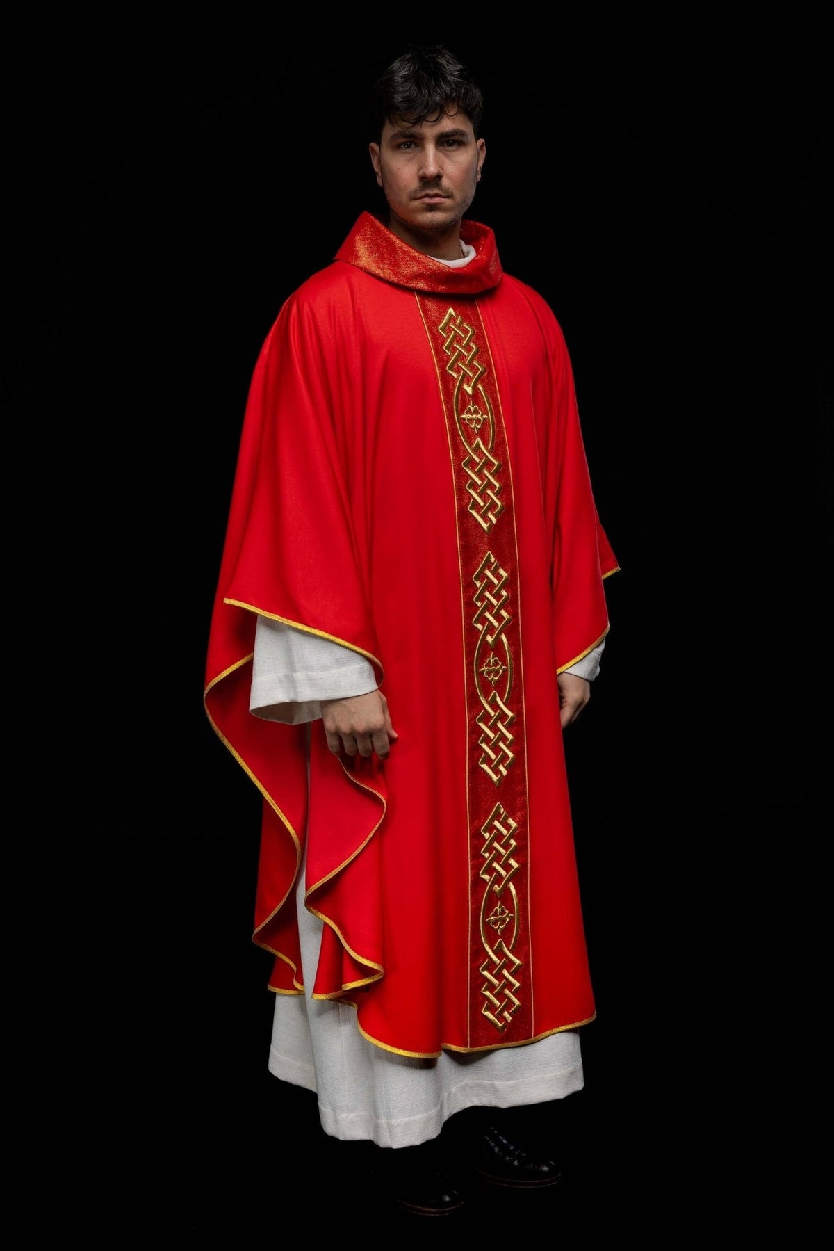 Red chasuble worn in a full front view, showing gold embroidered trim and central motif