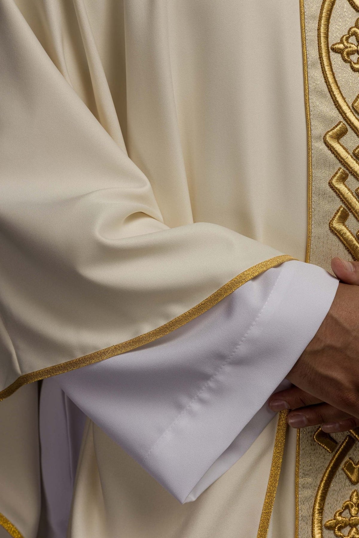 Ecru chasuble detail showing satin sleeve and gold trim