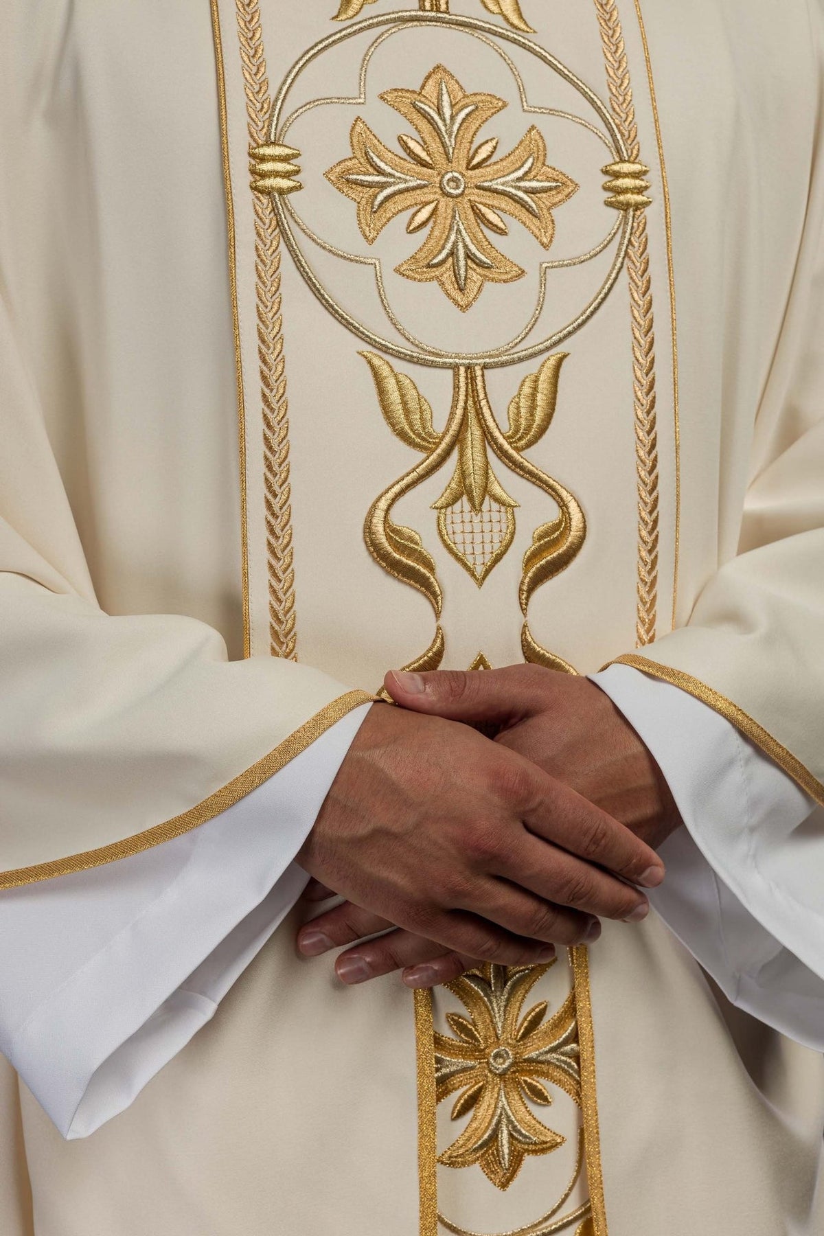 Ecru chasuble close-up showing gold embroidery and satin sleeve trim