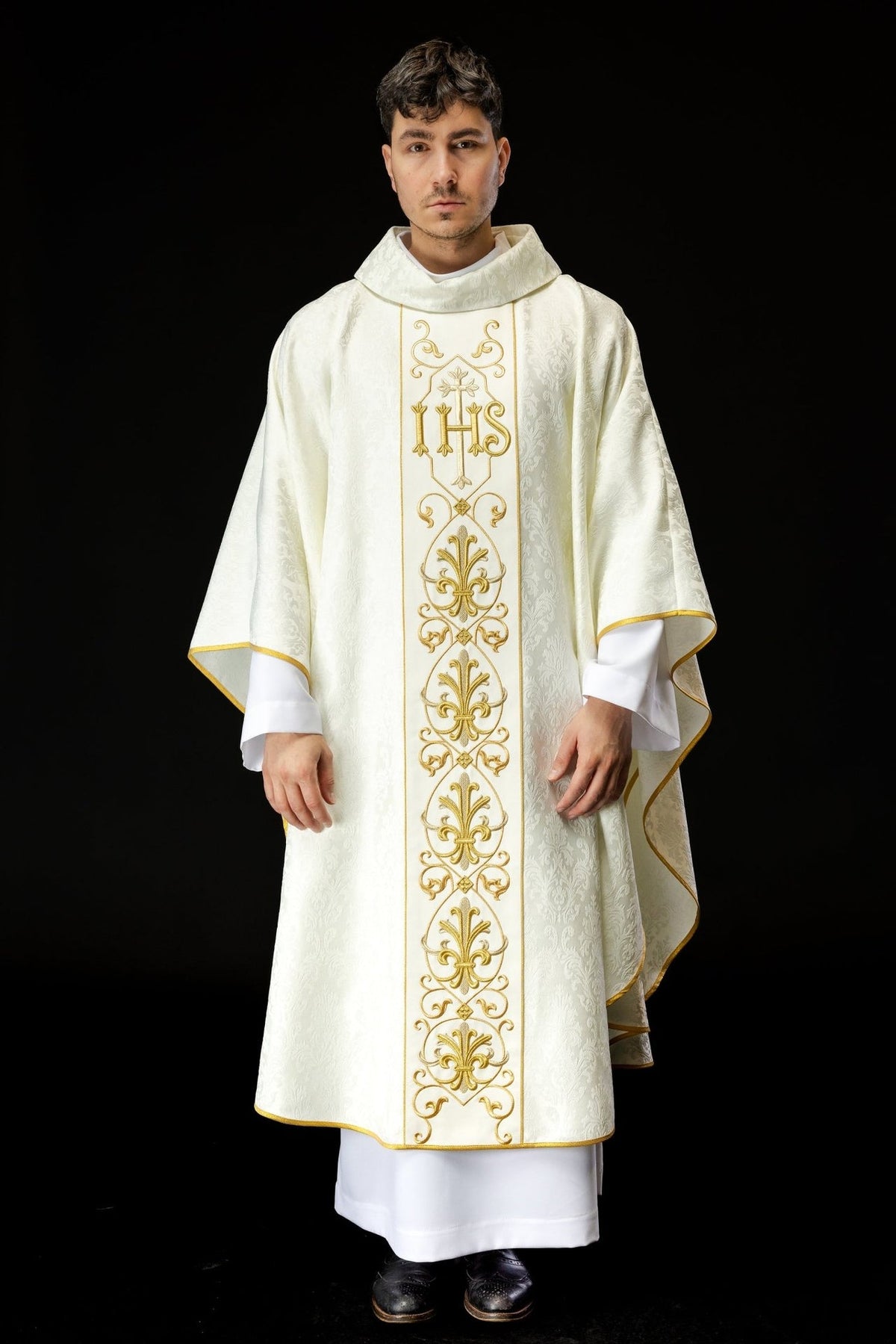 Ecru chasuble worn full-length from the front with gold IHS embroidery