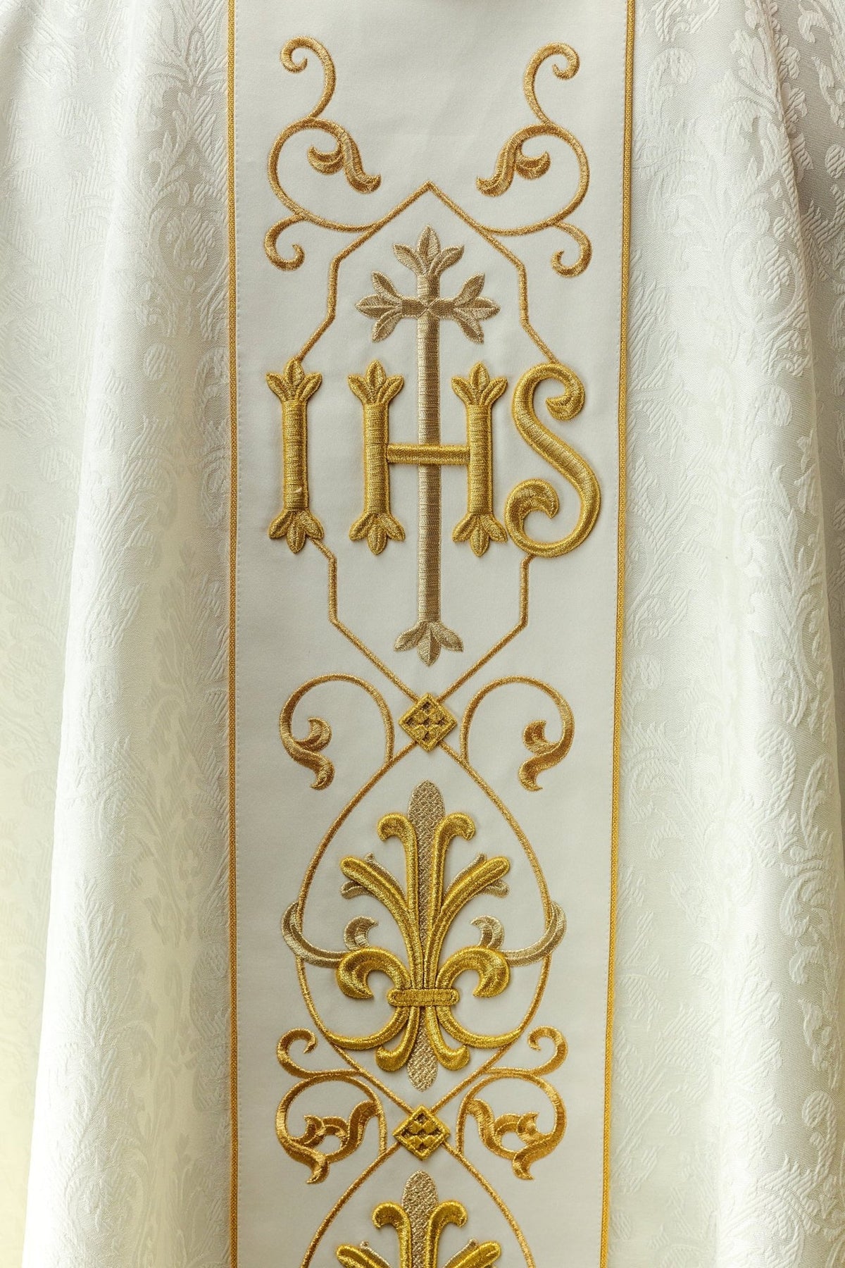 Ecru chasuble front close-up showing gold IHS embroidery and cross