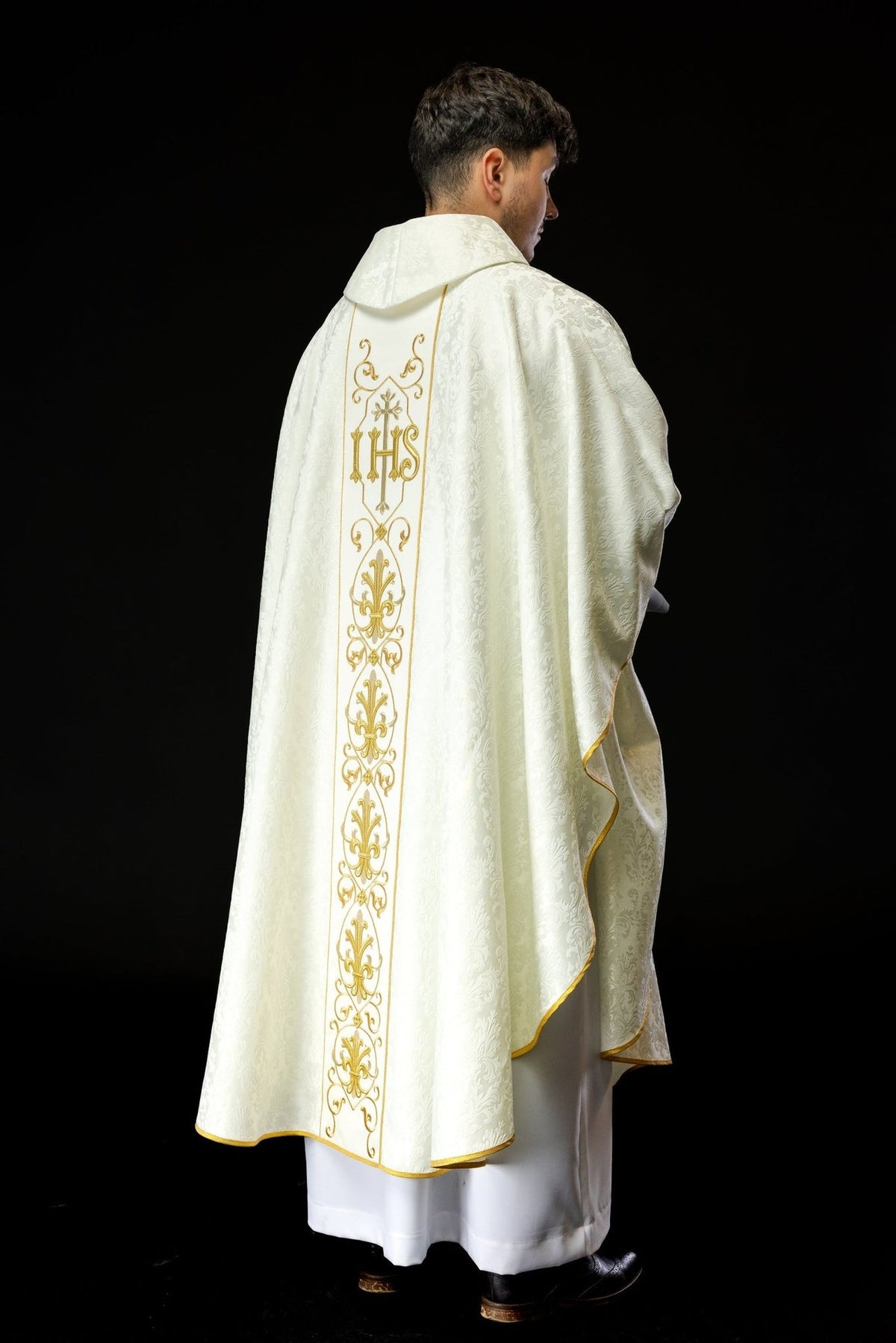 Ecru chasuble worn from the back with gold IHS embroidery and stand-up collar