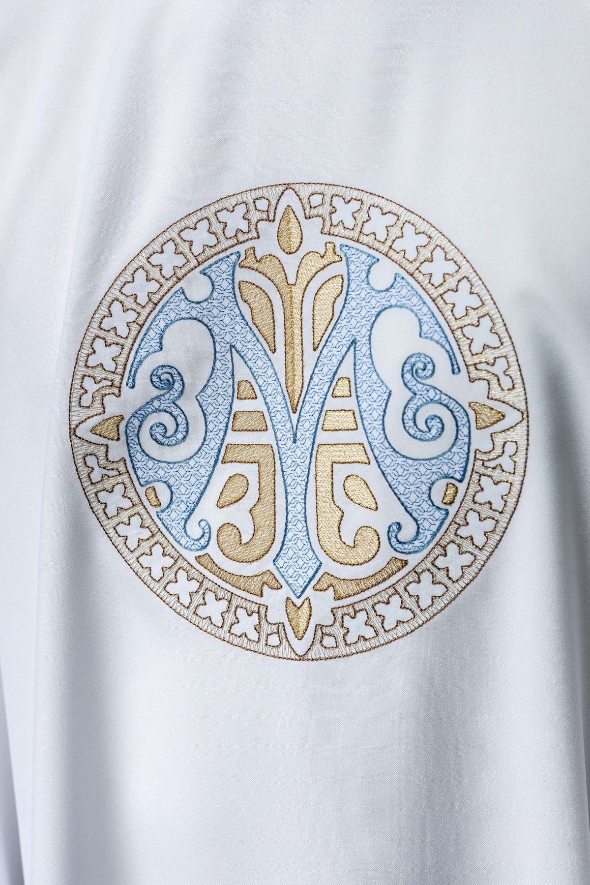Marian chasuble close-up showing the embroidered blue-and-gold Marian motif on white fabric