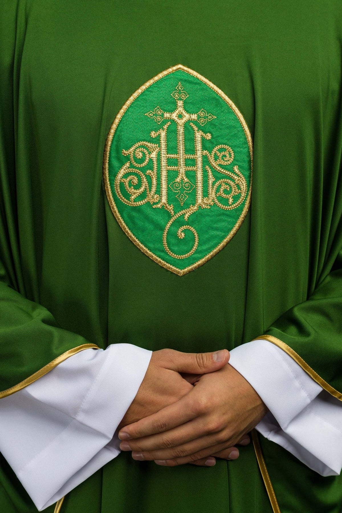 Green chasuble close-up with ornate gold embroidered cross motif and gold trim