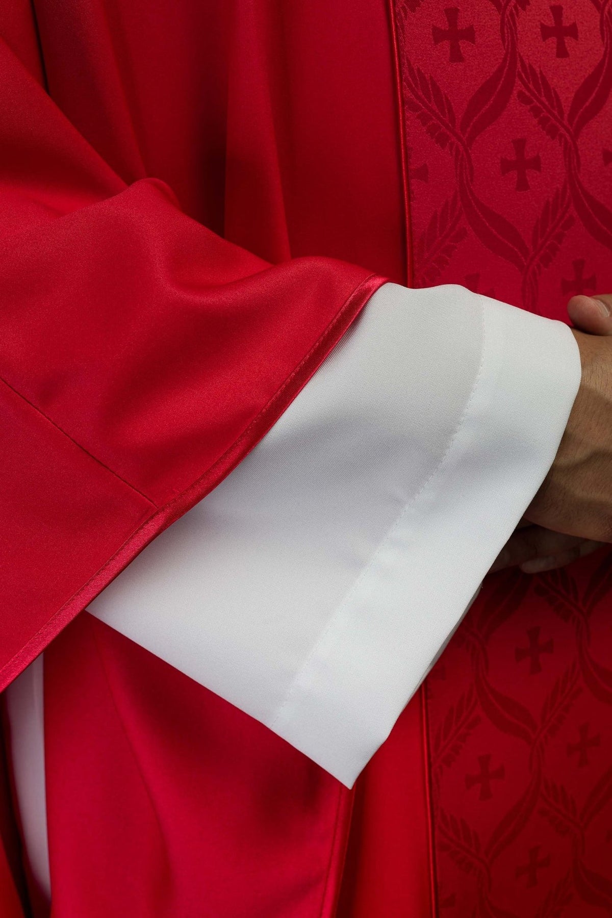 Red chasuble close-up showing satin trim and jacquard orphrey