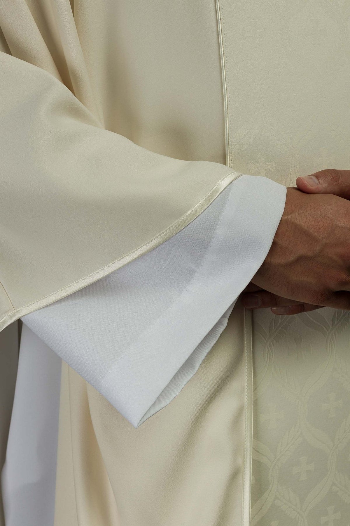 Ecru chasuble sleeve close-up with satin trim and white cuff