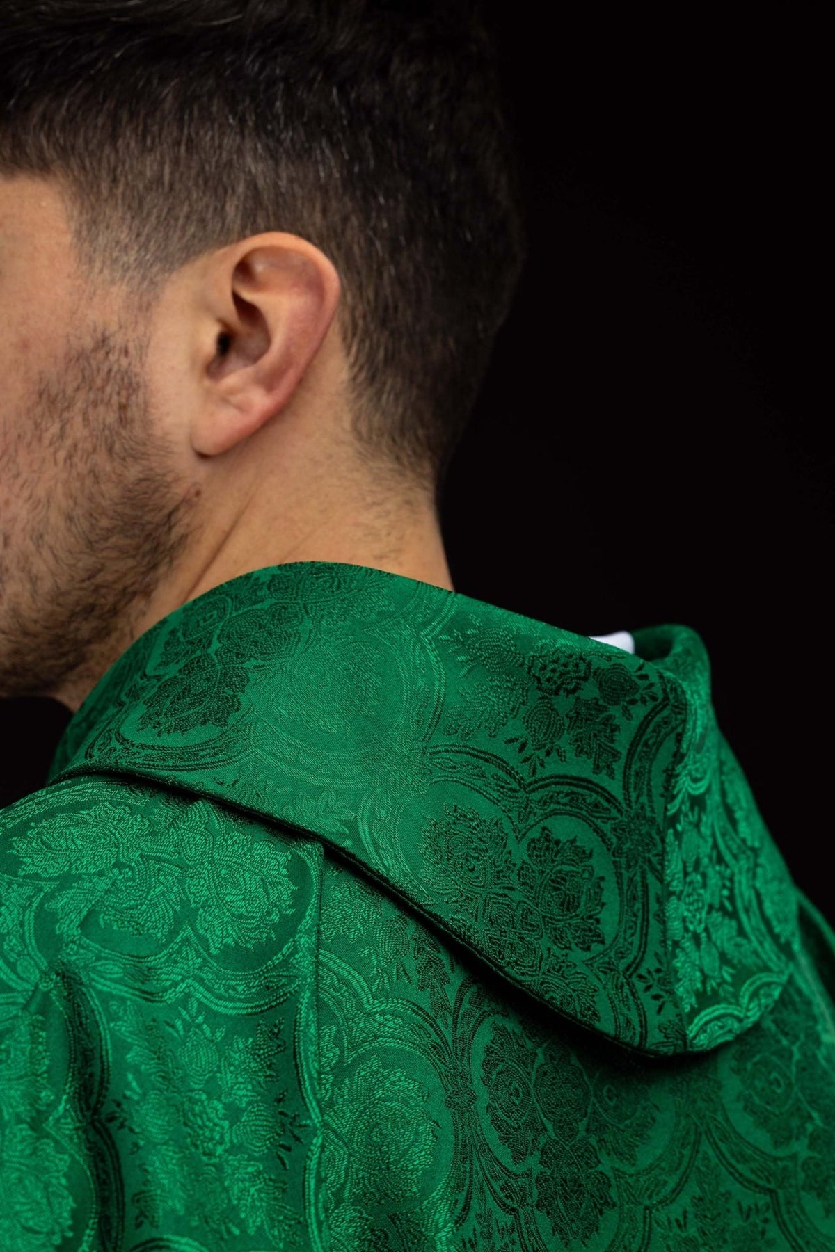Green chasuble close-up showing gold trim and jacquard fabric