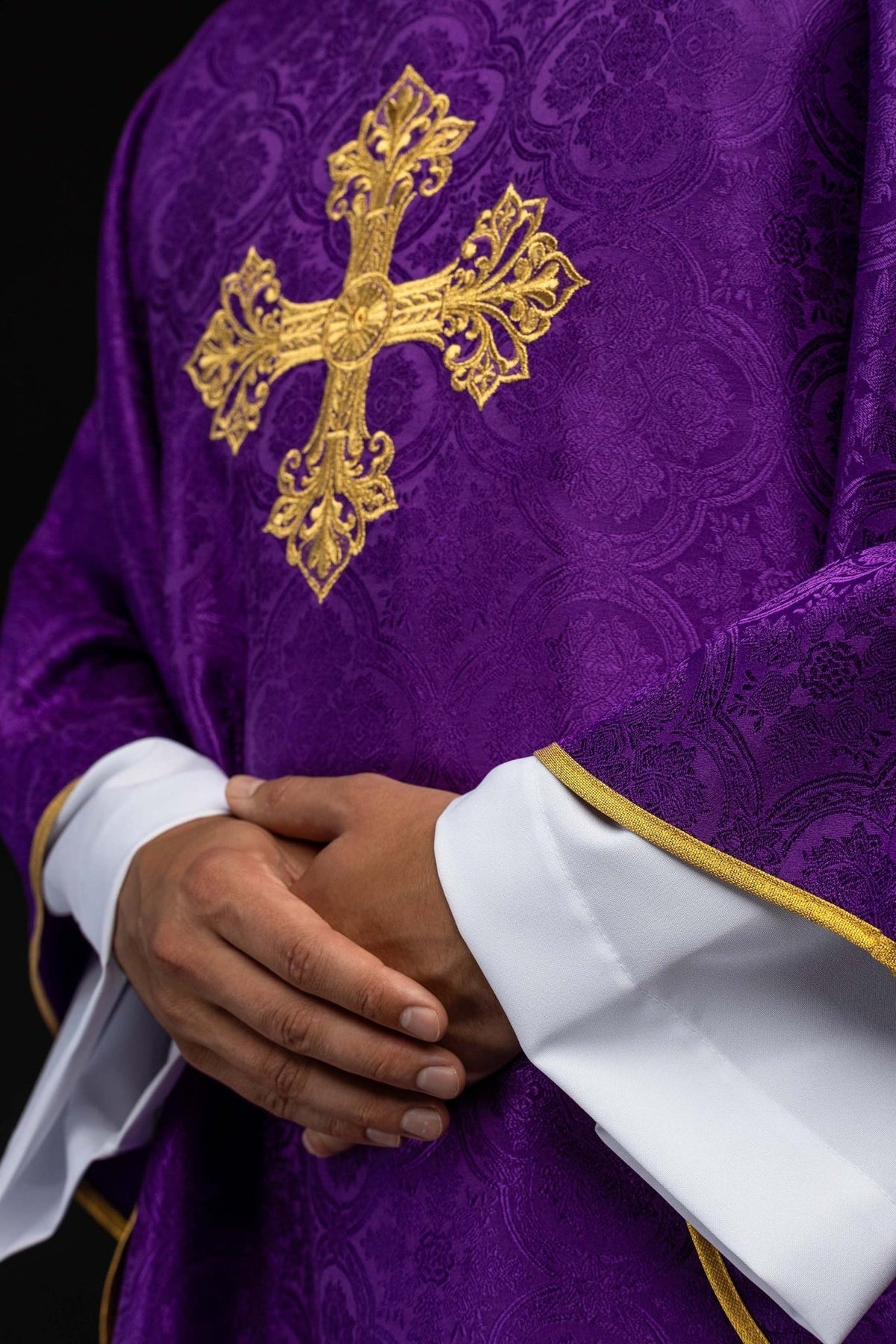 Purple chasuble close-up showing gold cross embroidery and gold sleeve trim