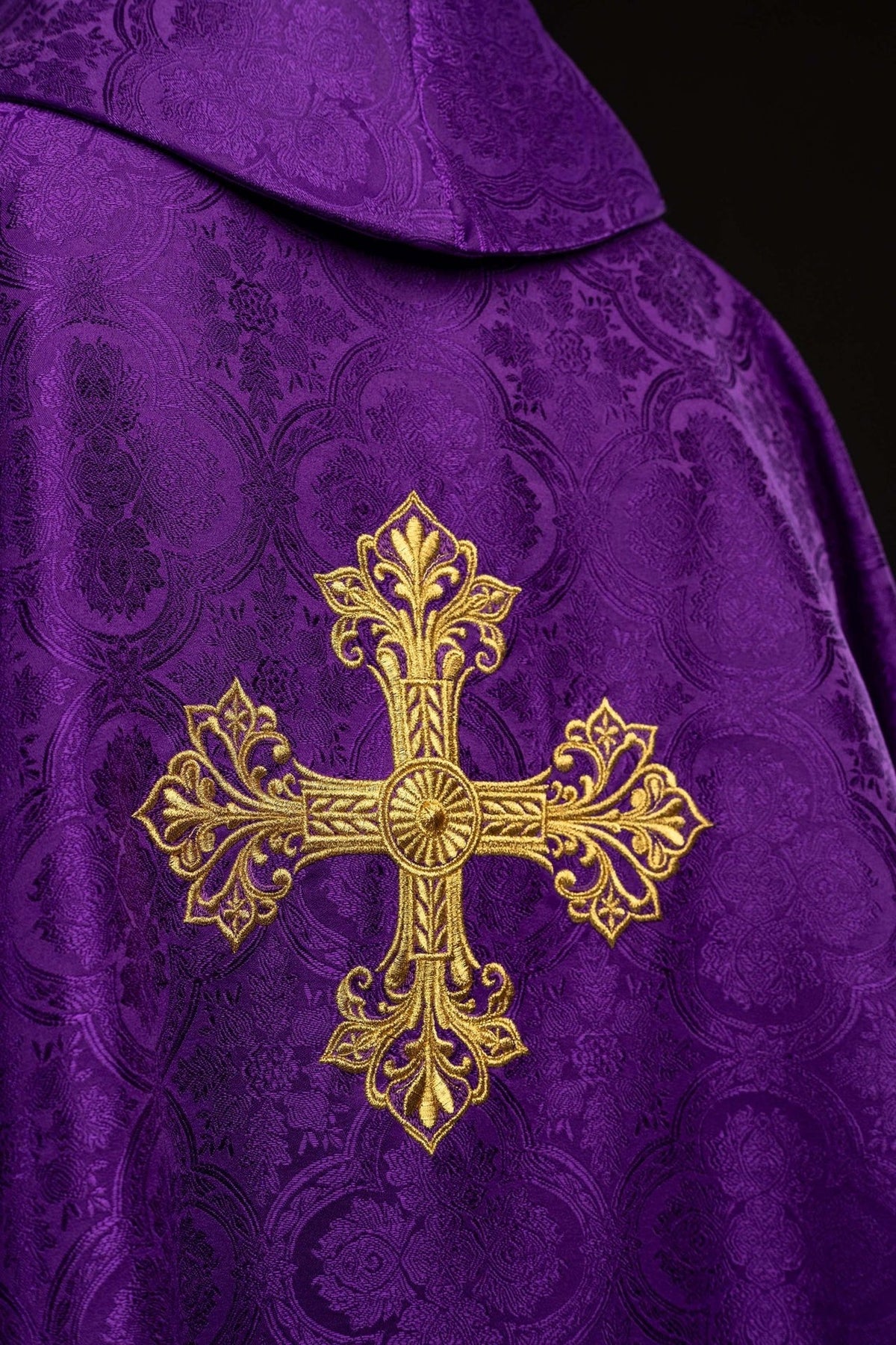 Purple chasuble back close-up with gold cross embroidery and patterned fabric