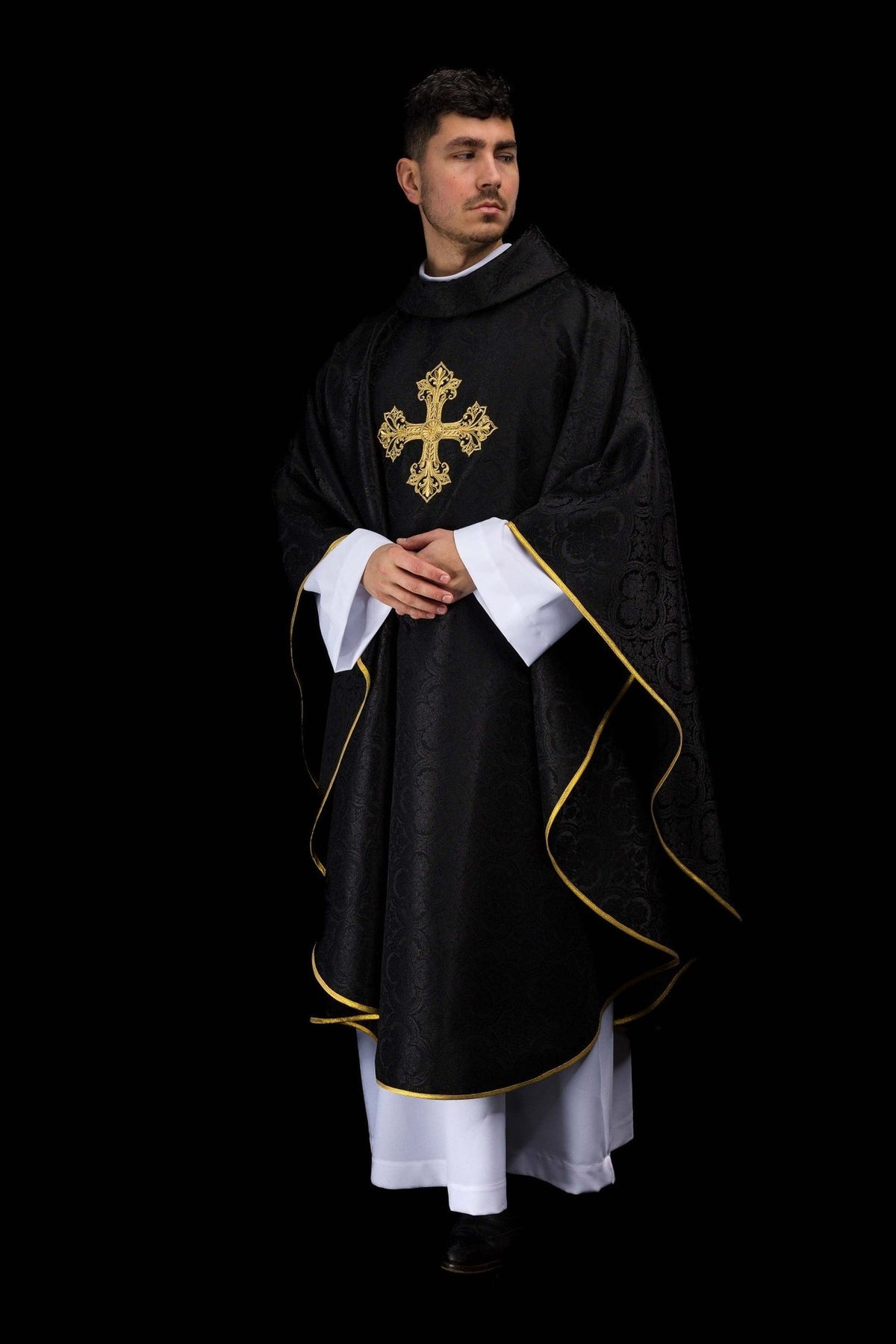 Black chasuble worn full length, showing gold cross, stand-up collar and gold trim