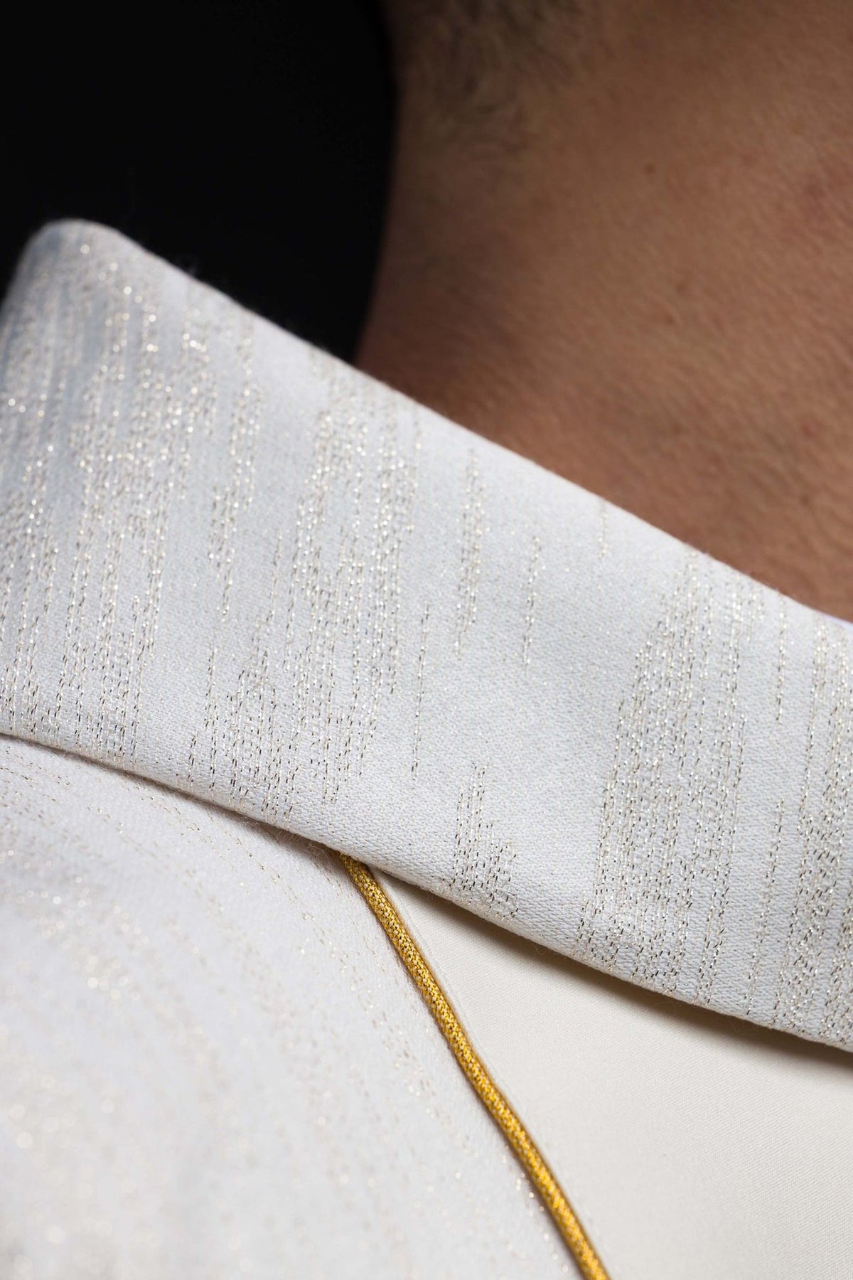 Chasuble fabric close-up showing ecru woven stripes and gold threads