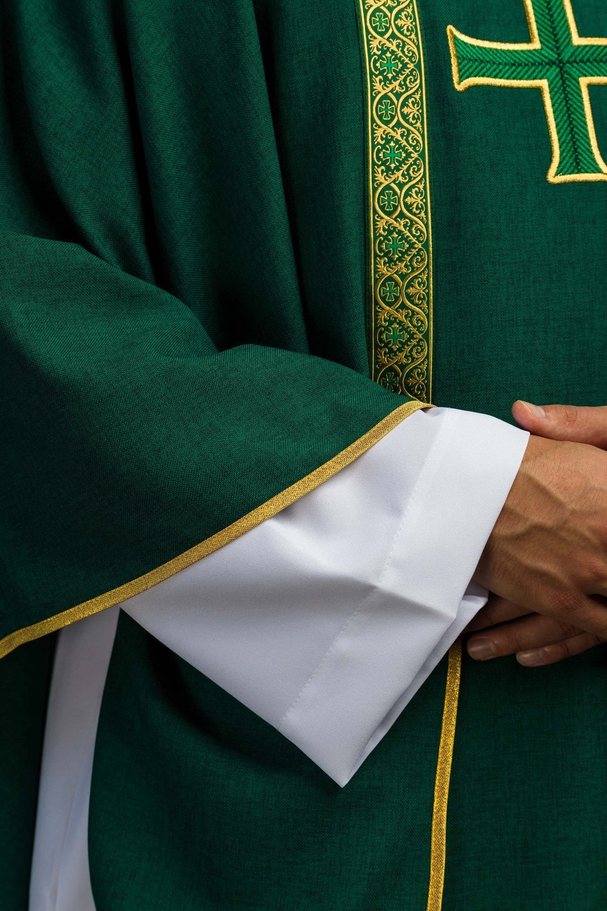Green chasuble sleeve close-up with gold trim and white cuff visible