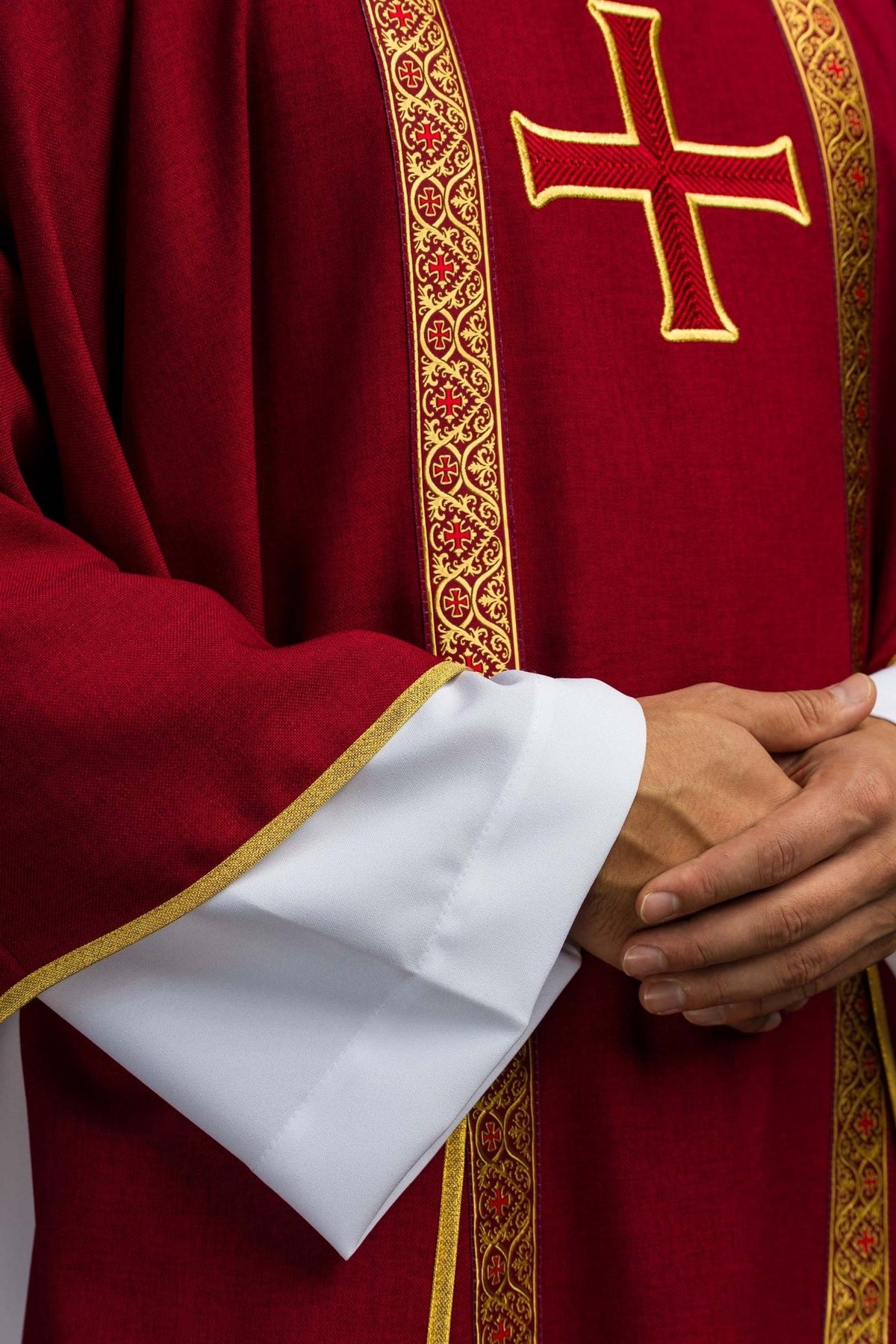 Red chasuble detail showing gold trim, embroidered cross and patterned orphrey