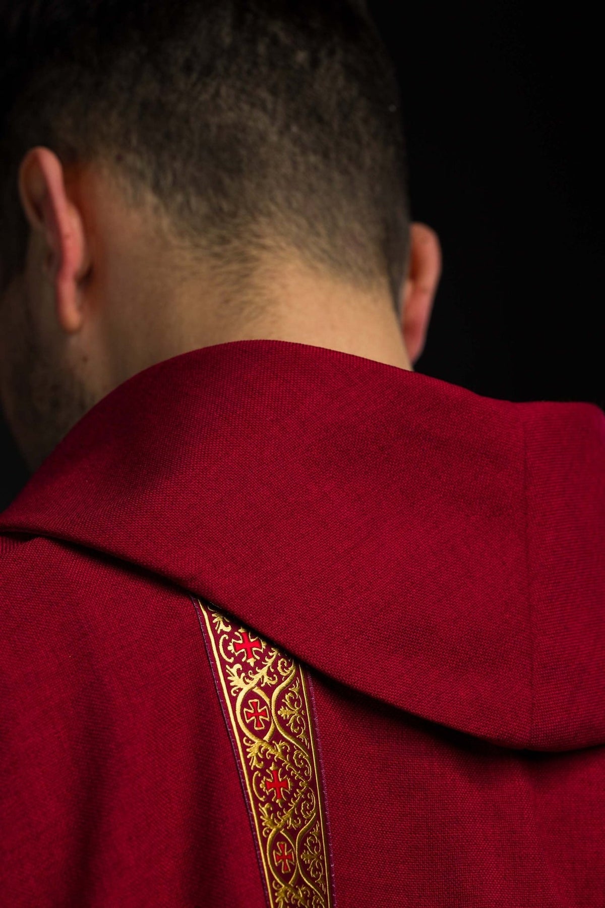 Red chasuble close-up showing sleeve trim and jacquard orphrey
