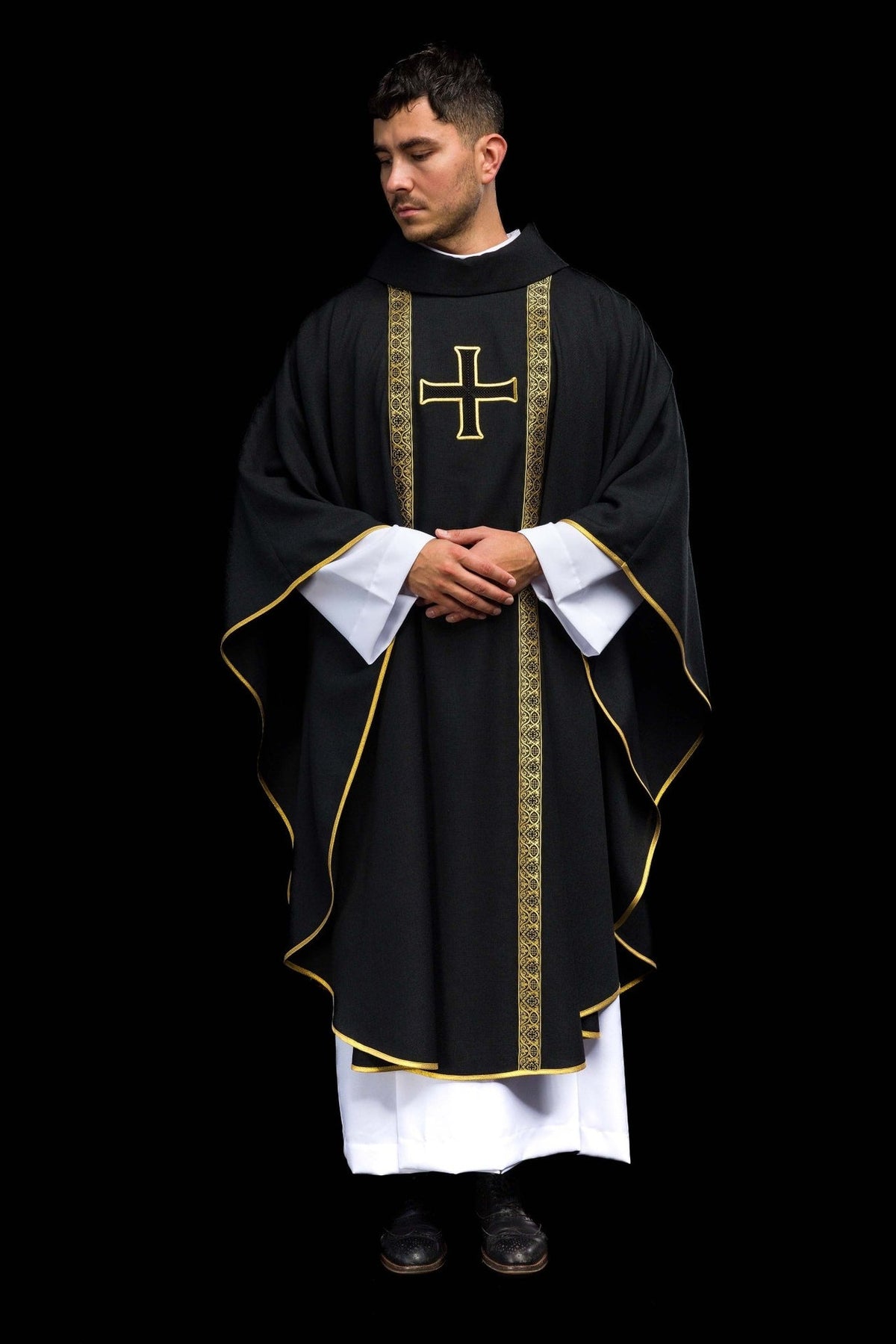 Black chasuble worn front view with gold trim, cross embroidery and jacquard orphrey