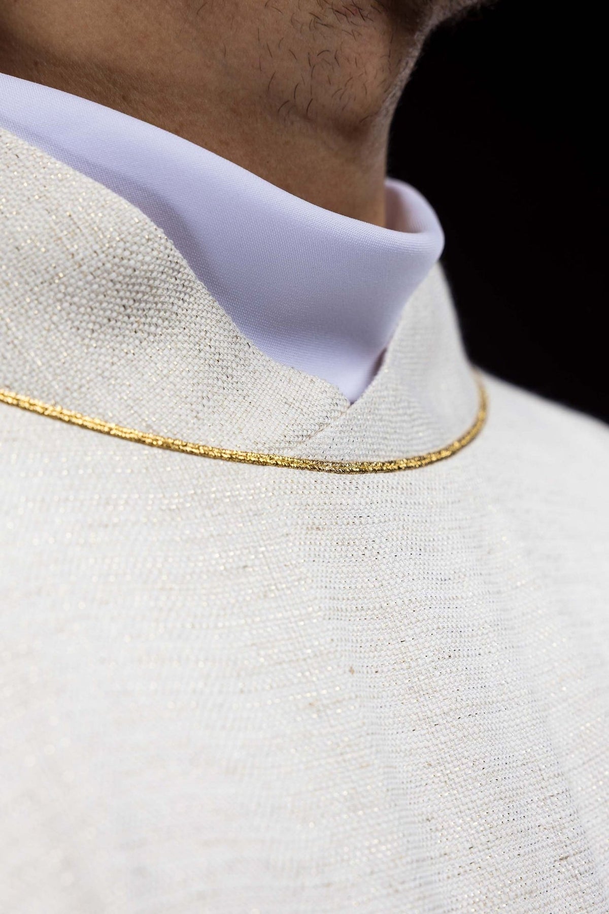 Chasuble close-up showing ecru fabric and gold stand-up collar trim