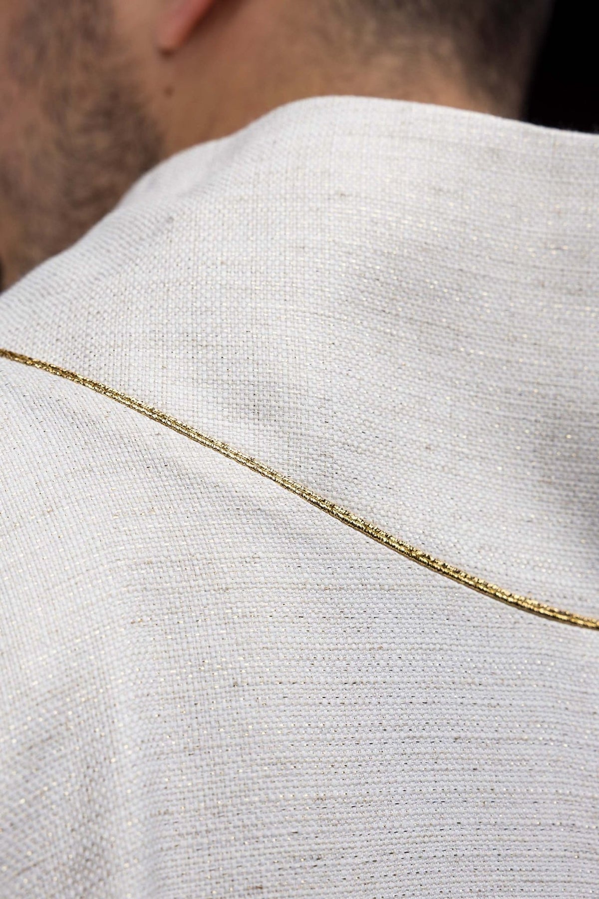 Chasuble close-up showing ecru fabric and gold edge trim