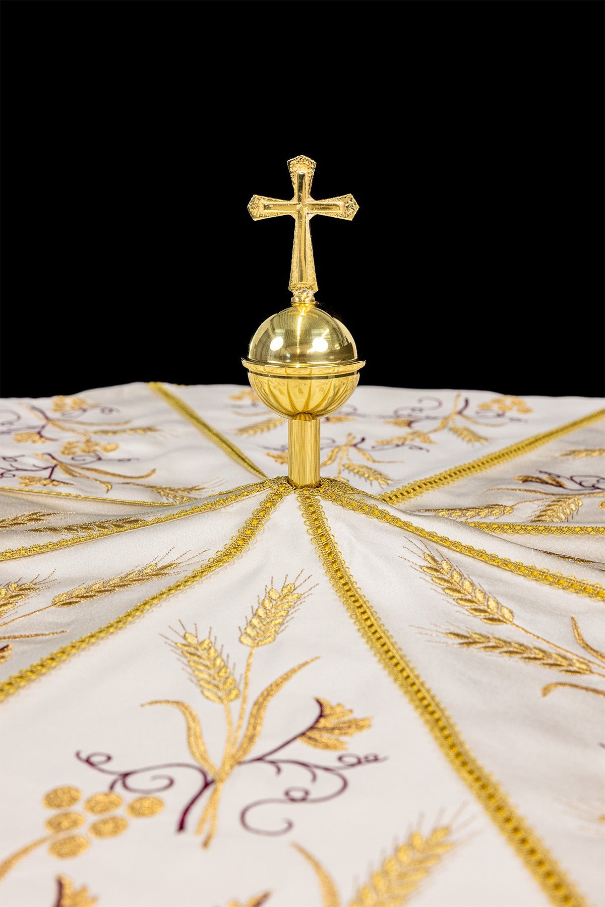 Ecru processional umbrella detail showing gold cross finial and embroidered panels