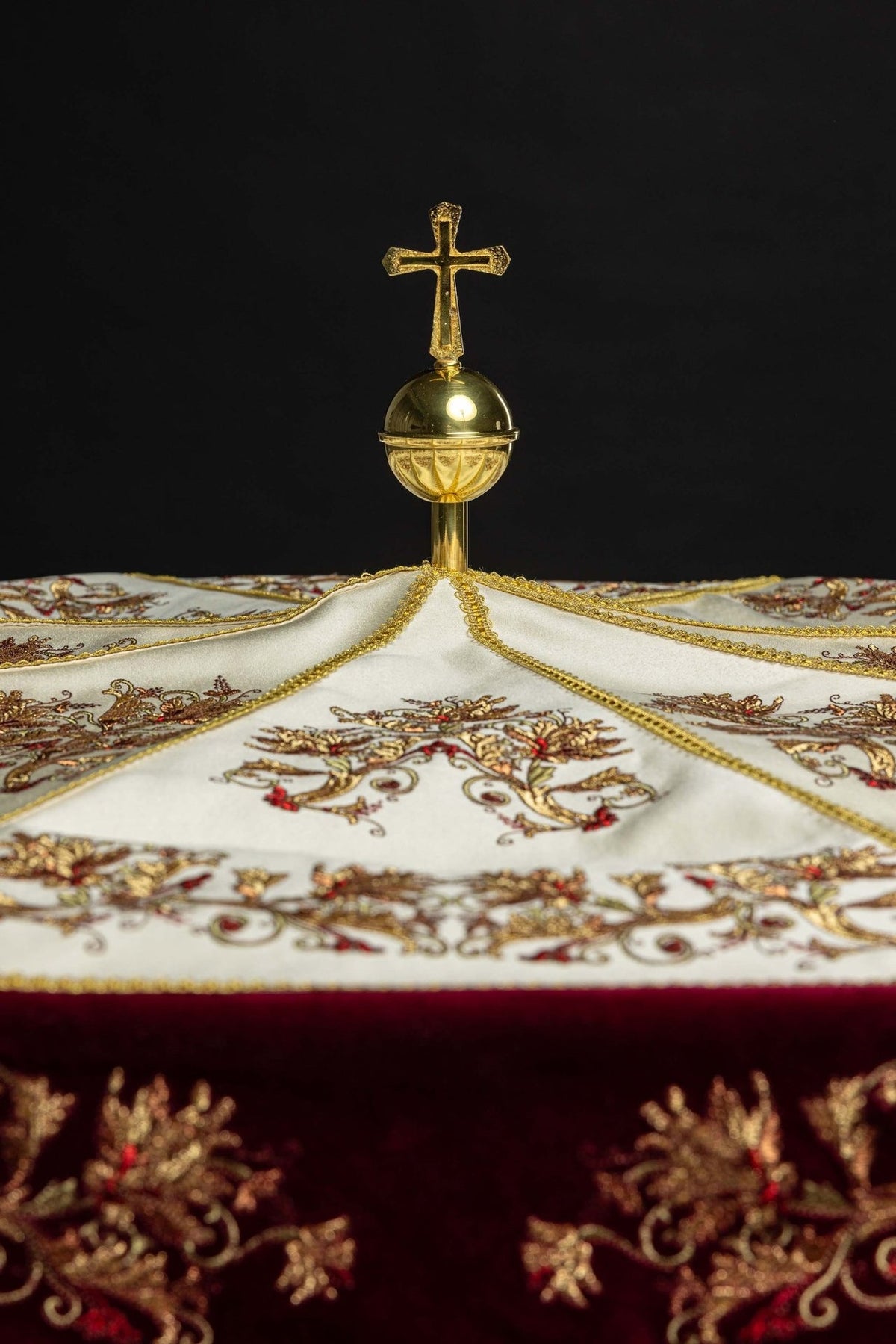 Processional umbrella close-up of gold cross finial and embroidered ecru canopy